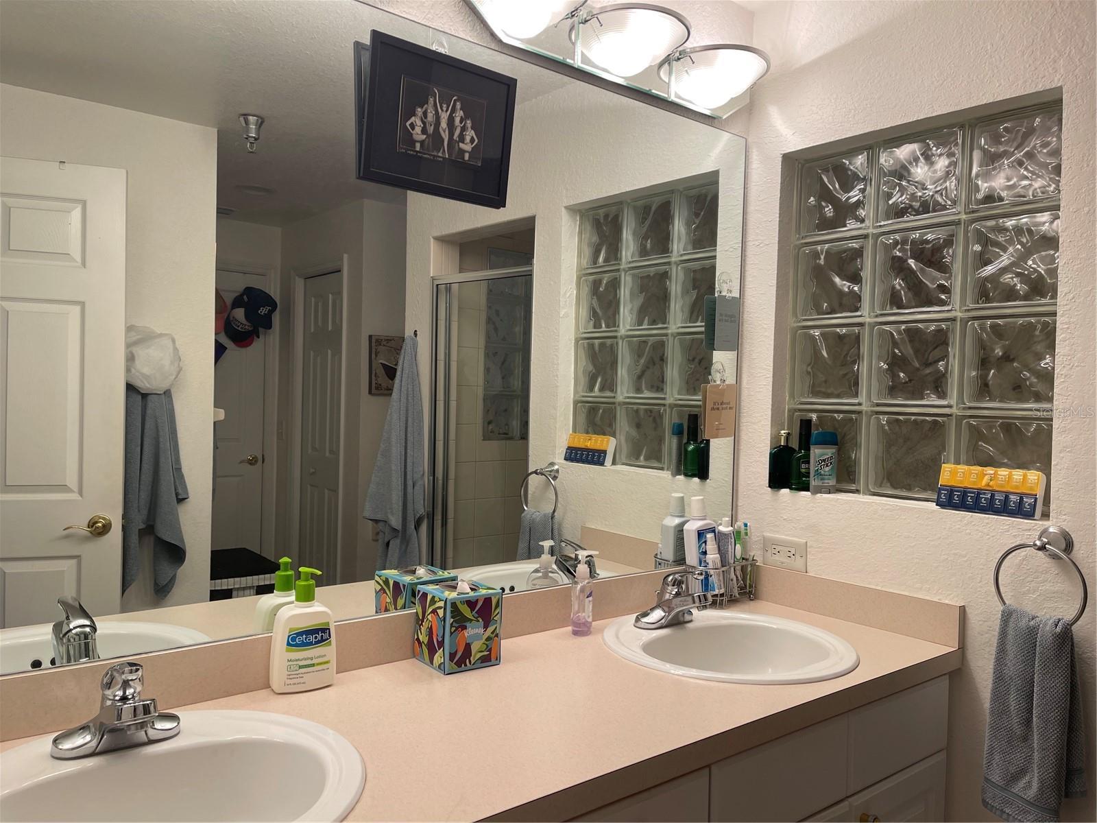 The primary bathroom has a double vanite, Behind the glass block is the shower.