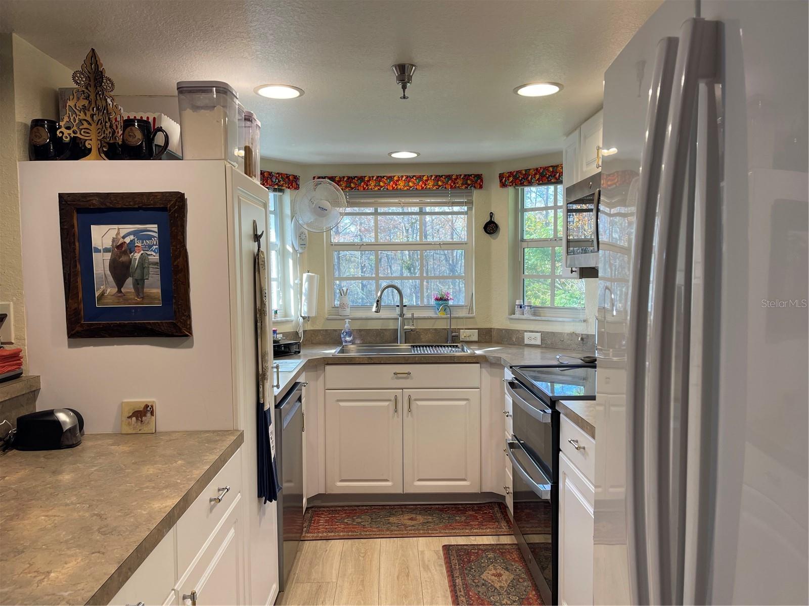 The kitchen sink has been updated to a farm sink. Appliances include dishwasher, disposal, microwave, range, and side by side refrigerator.