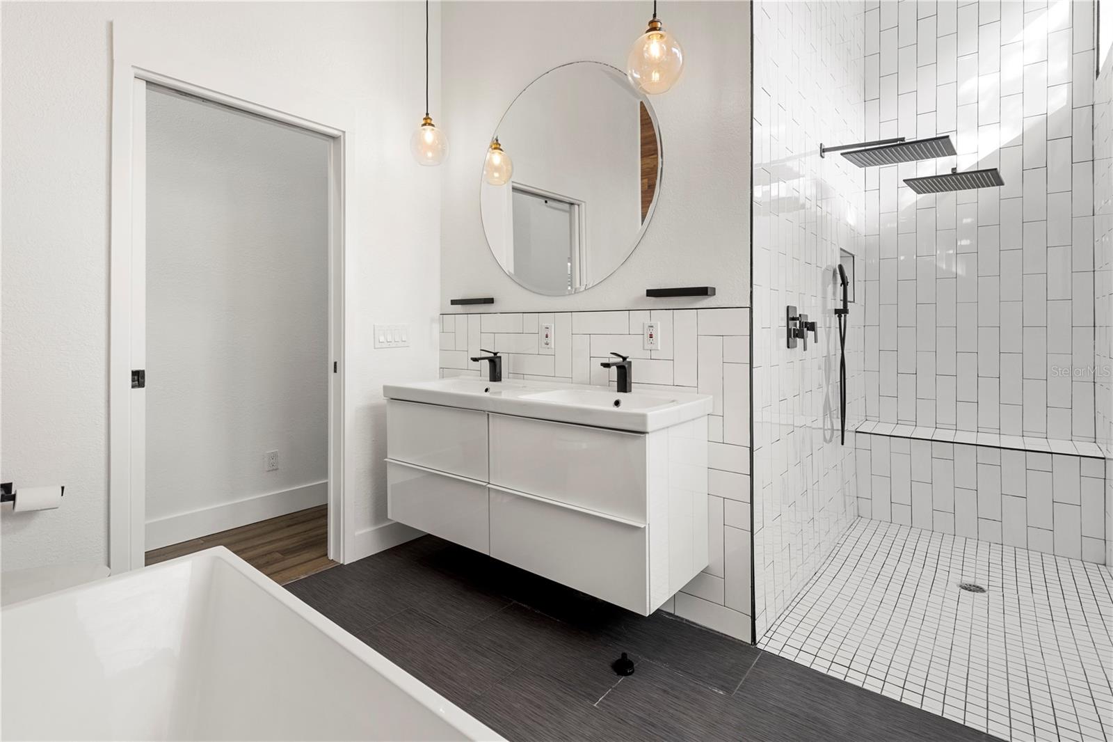 Indulge in the spa-like master bathroom featuring a luxurious 6’ soaking tub, dual rainfall shower heads, and sleek modern finishes—your personal oasis in South Tampa.