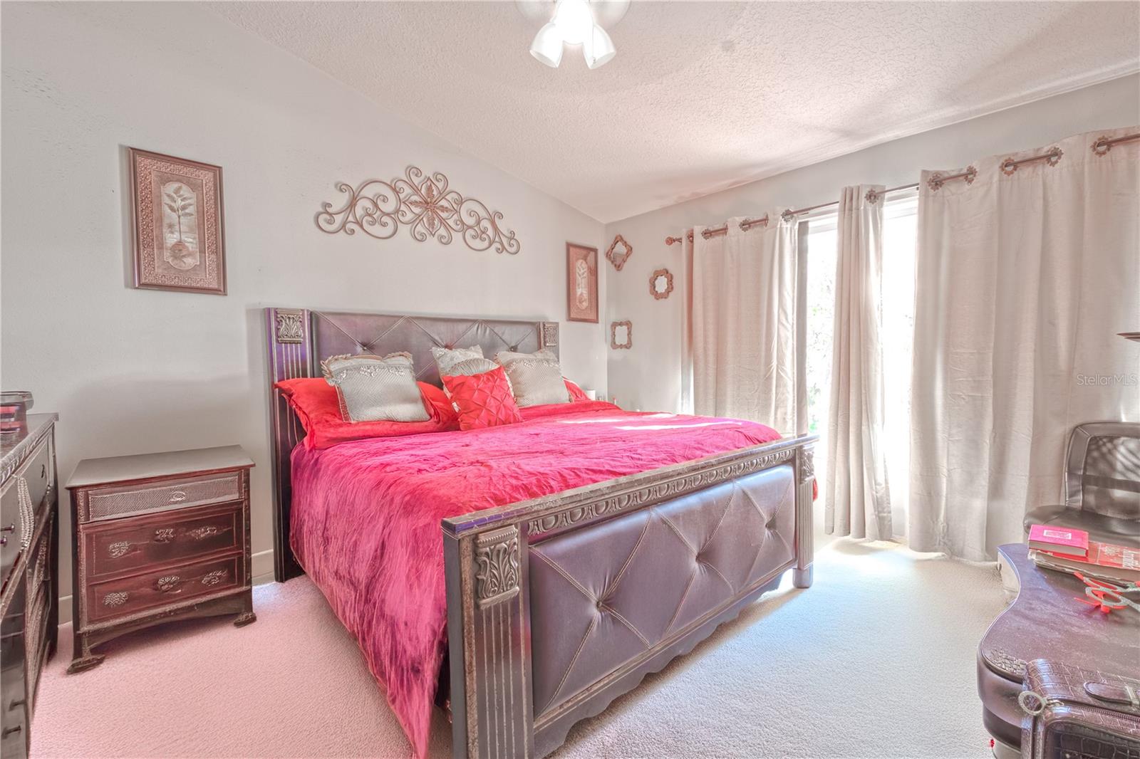 The Primary bedroom  features neutral tone walls and carpet, a ceiling fan with light kit, a built-in closet and vaulted ceiling.