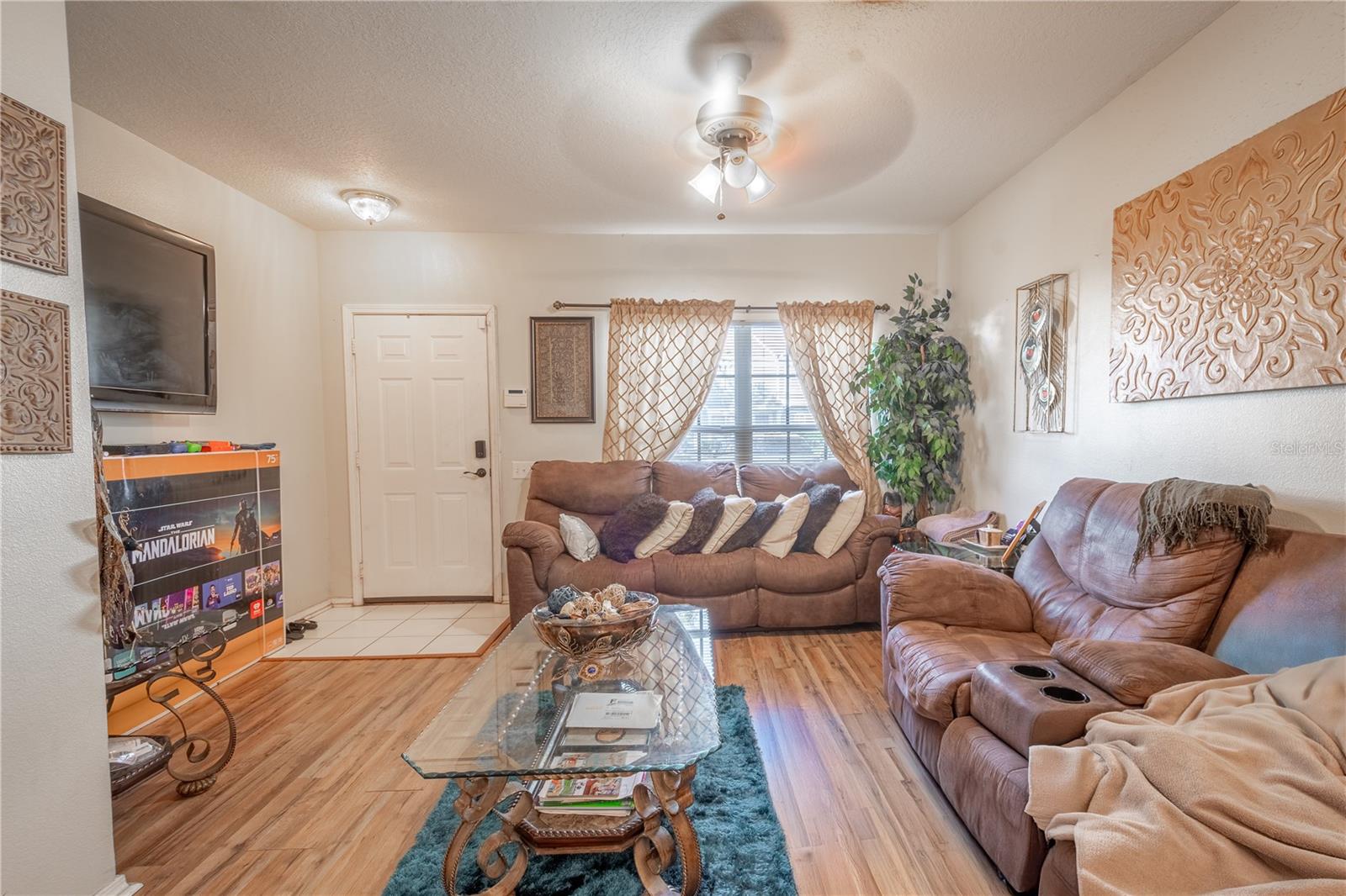 The Living room features neutral tones, wood laminate flooring, a ceiling fan with light kit and picture window.