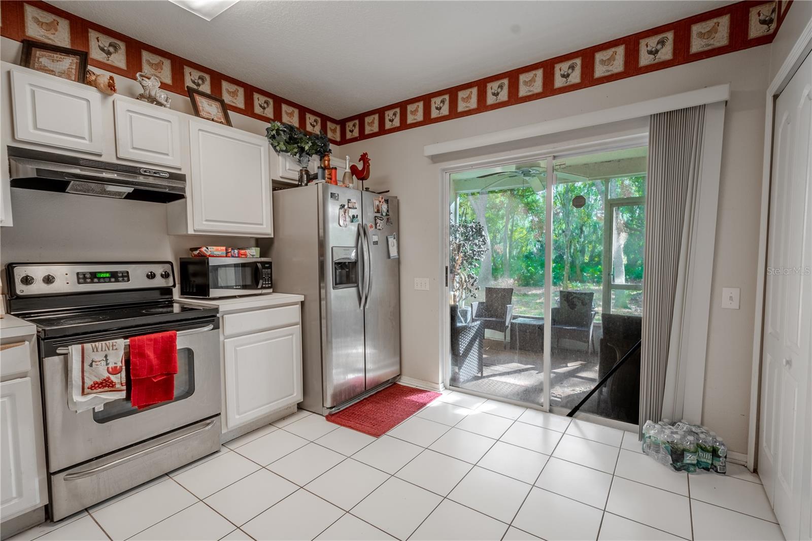 Kitchen features ceramic tile flooring, stainless steel appliances including a French door refrigerator with ice maker and water dispenser, an electric range and sliding glass door to the private screened in patio.