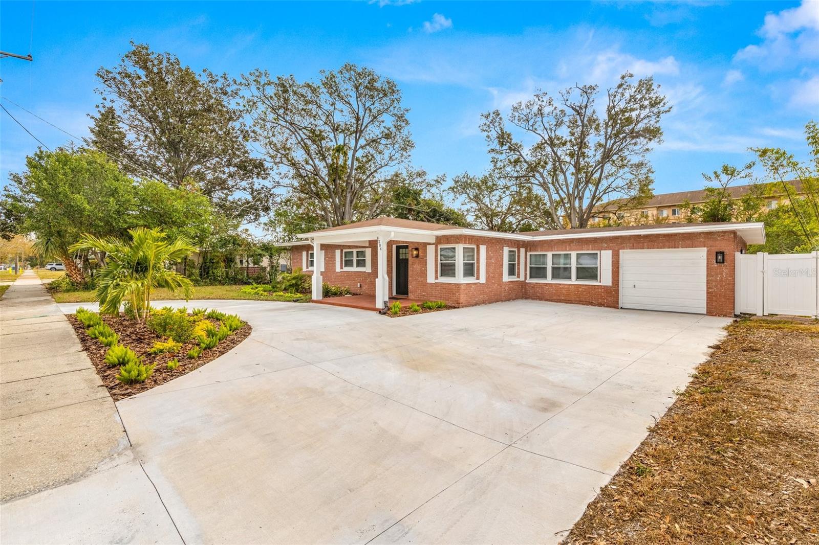 Landscaped curb appeal with circular driveway, garage and additional parking area