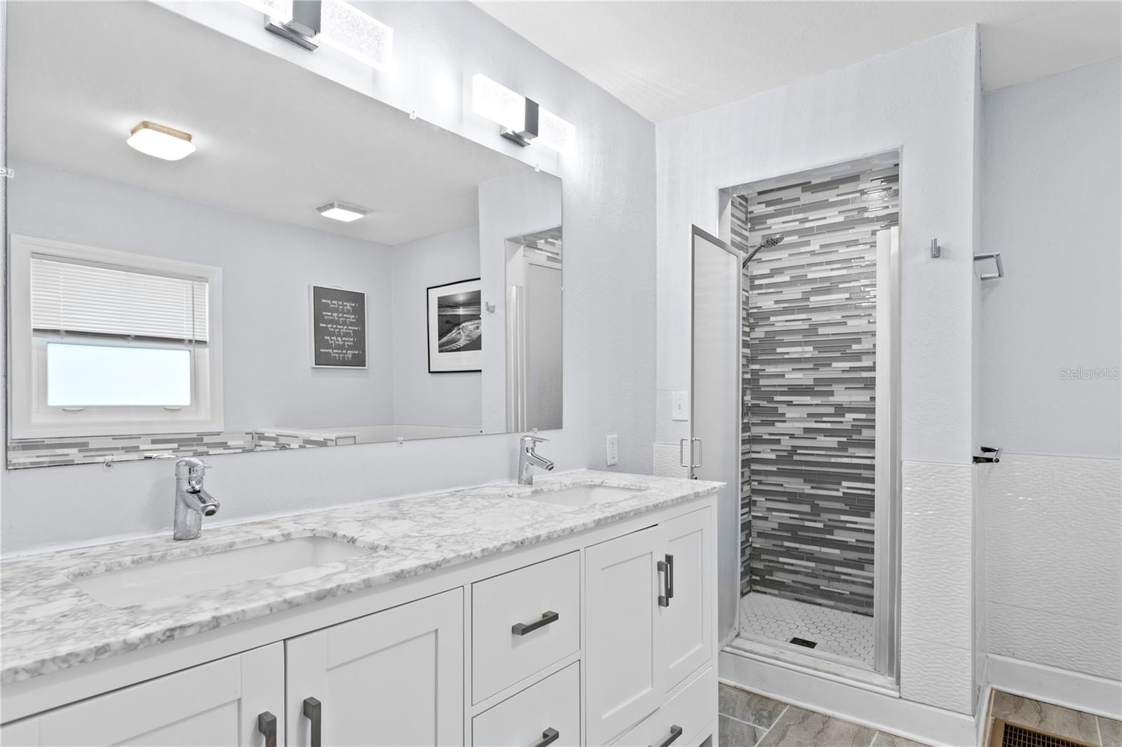 Primary bath includes dual sinks, walk-in tiled shower and tile flooring