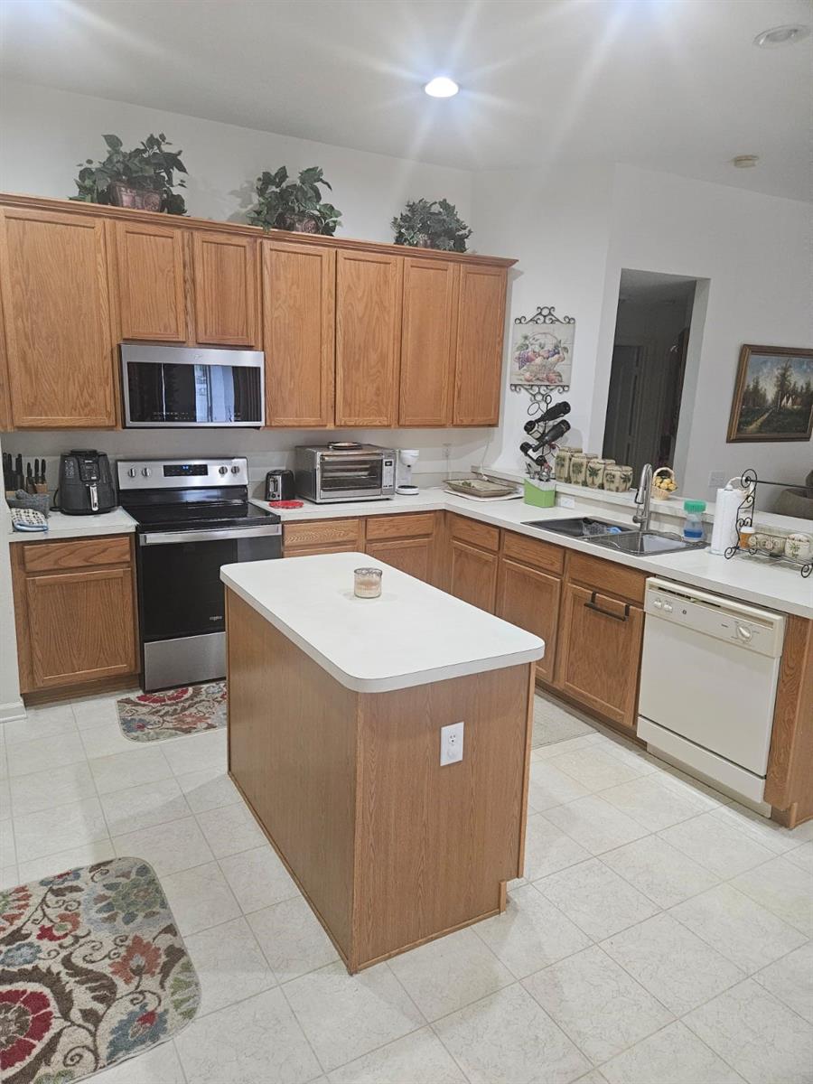 Kitchen has tile flooring, wood cabinets, the island, double bowl sink, wall mounted microwave just to mention a few.