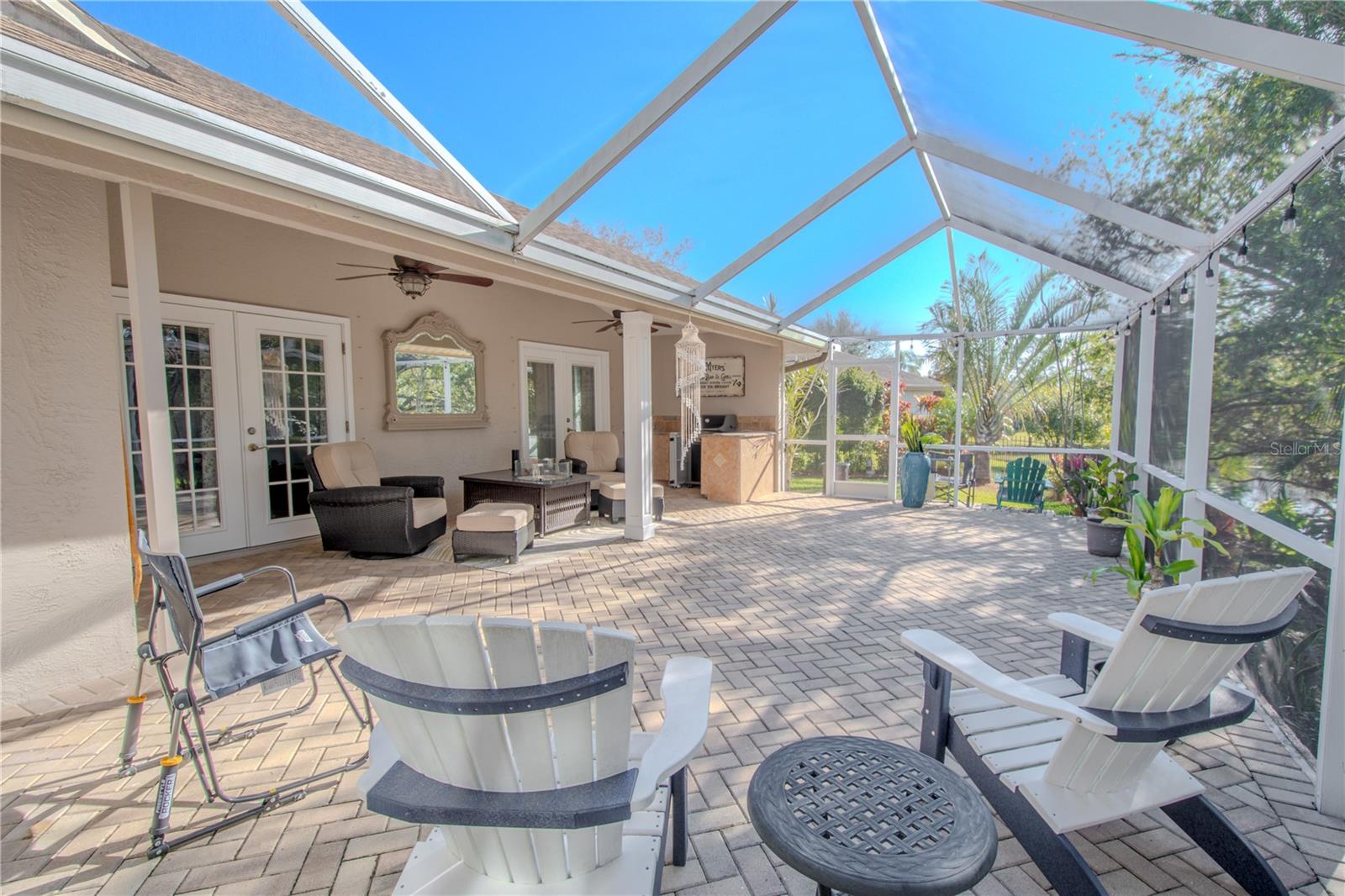 The partially covered, screened in lanai, brick-pavered lanai has a high screen for a light and airy feel.