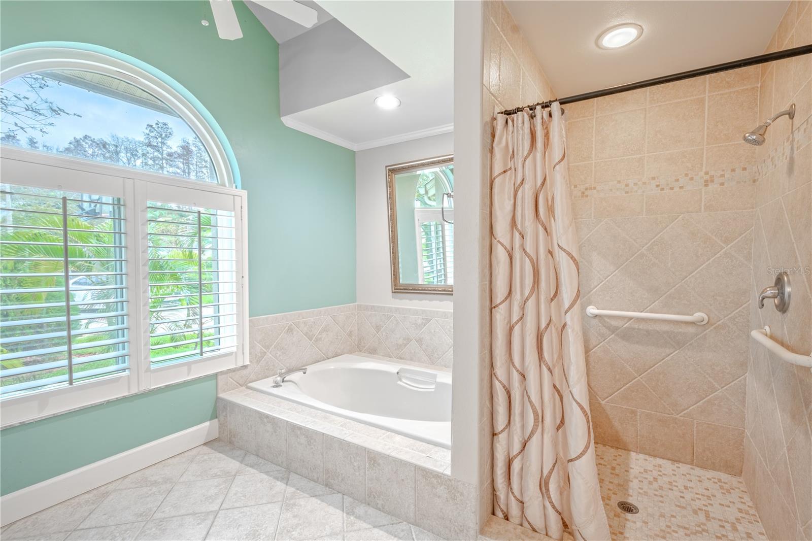 The primary bath features a garden tub and a separate walk-in tub and a stunning arched window with shutters.