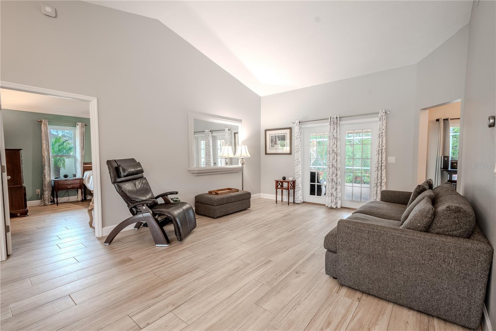 The spacious living room features a vaulted ceiling and French doors that lead to the screened in lanai and private backyard.