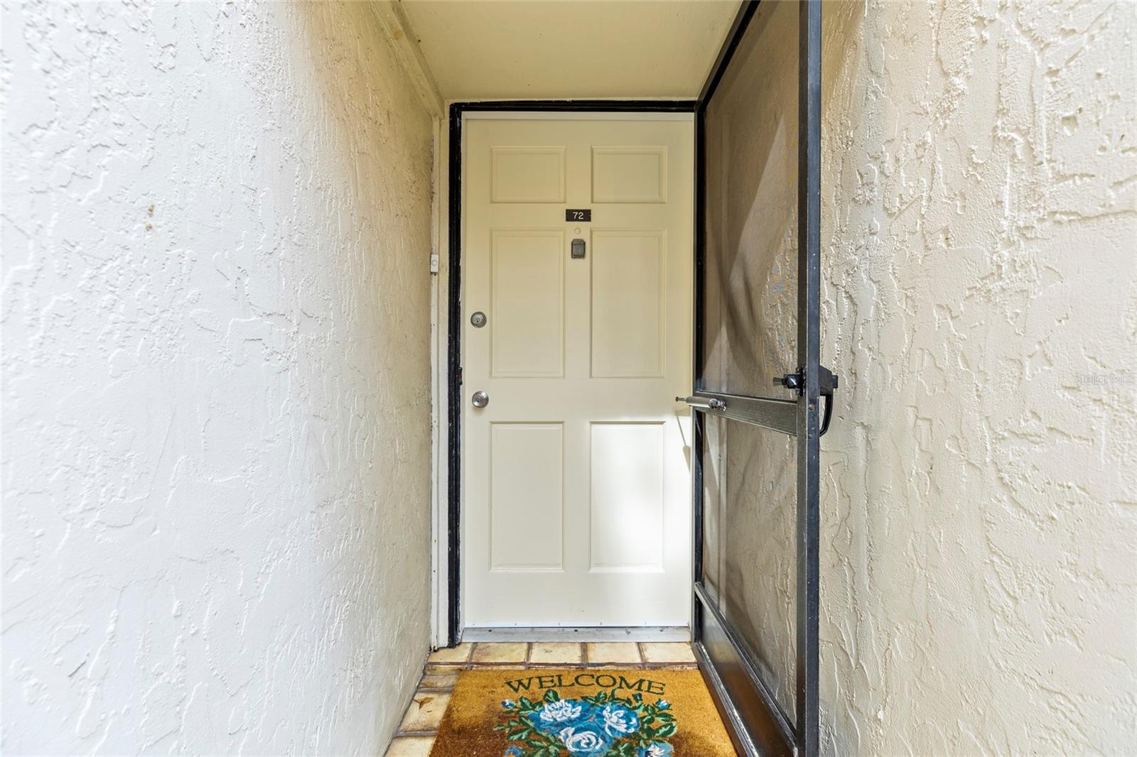 Covered front door with a screen door.