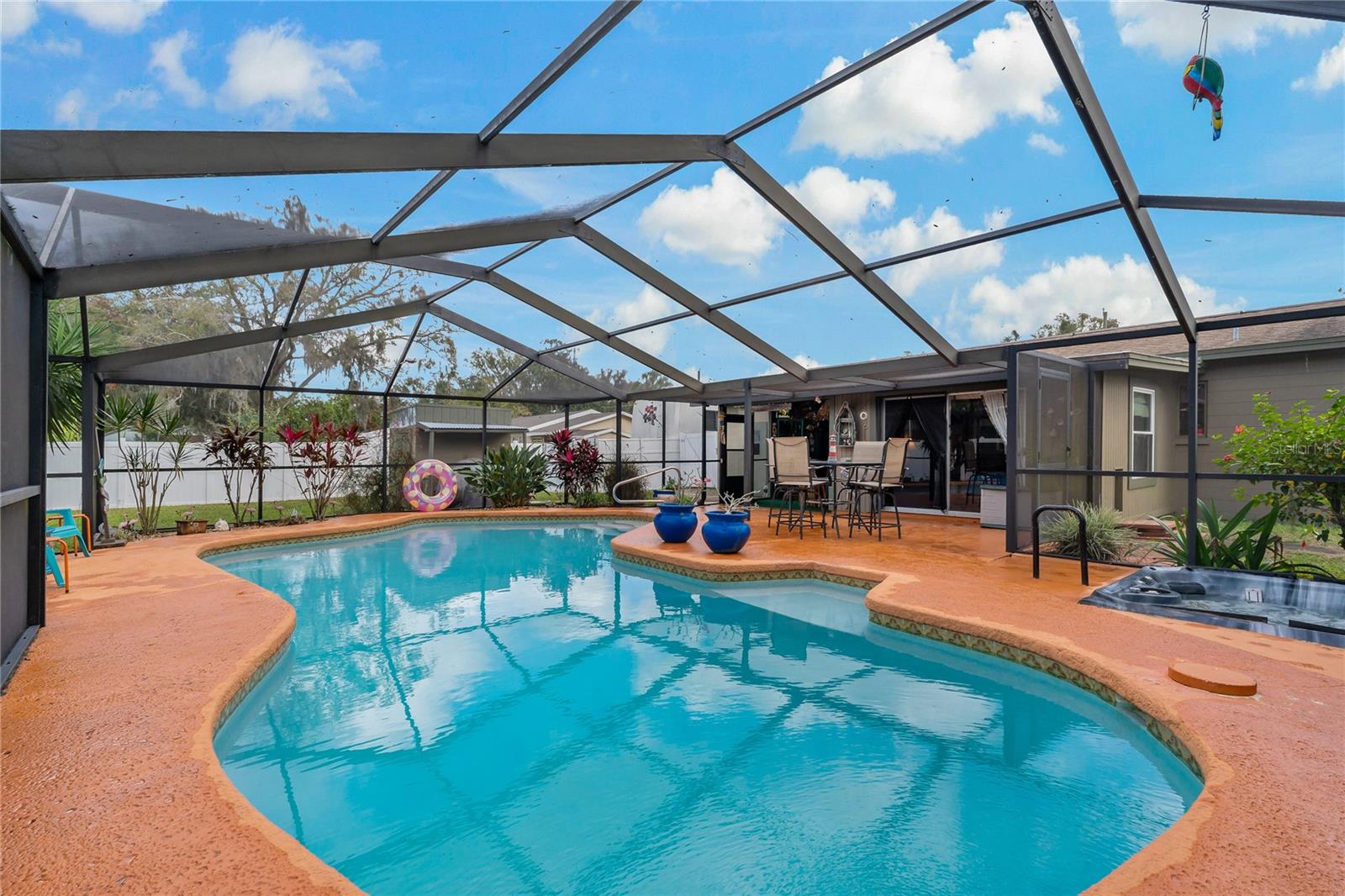 Screened Pool with carved swimout and hot tub to the right.