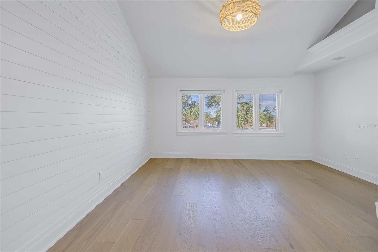 Primary bedroom with engineered white oak flooring and motorized black out shades on the windows