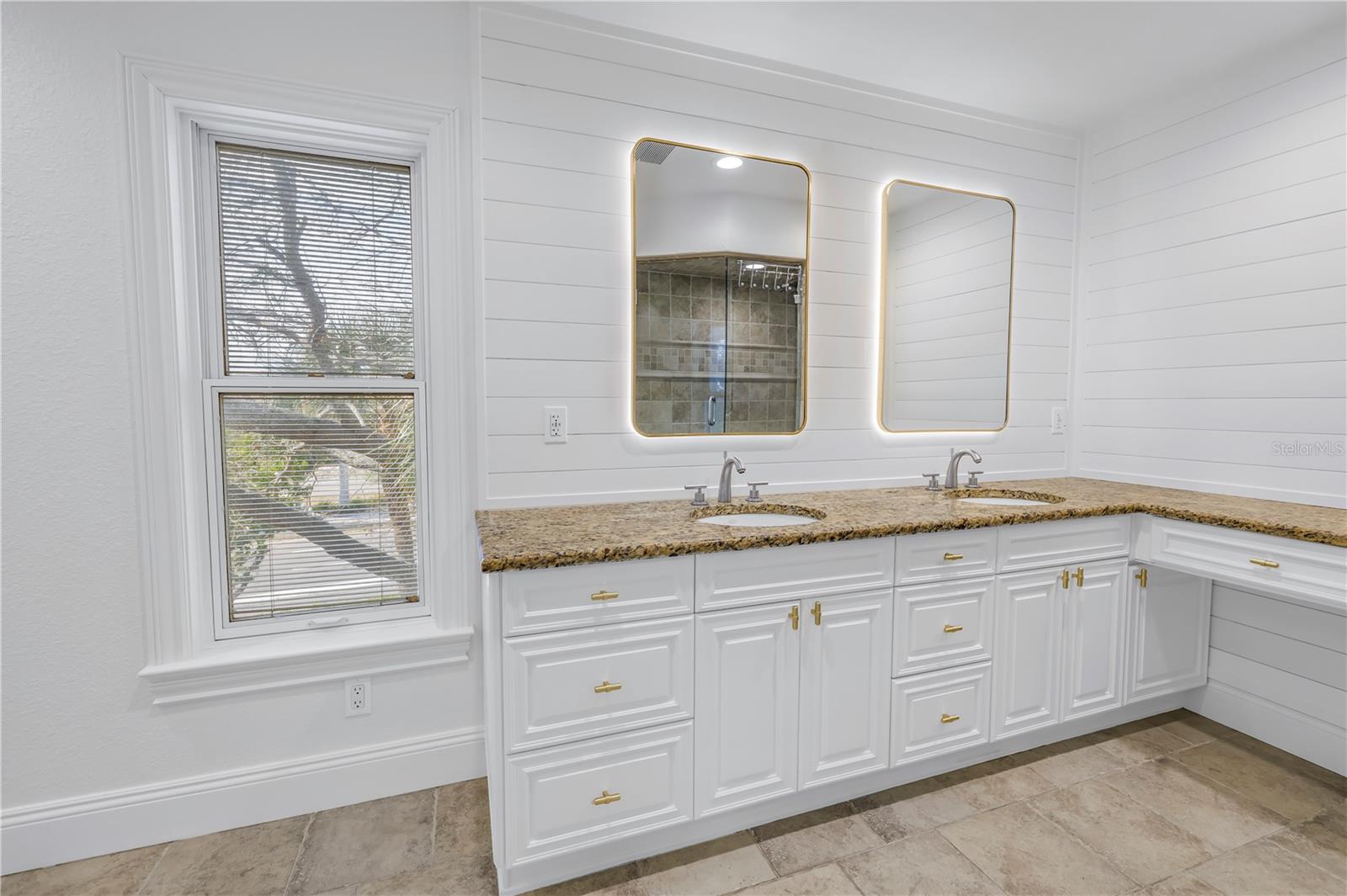 Primary bath with double Kohler sinks, granite counters and backlit mirrors