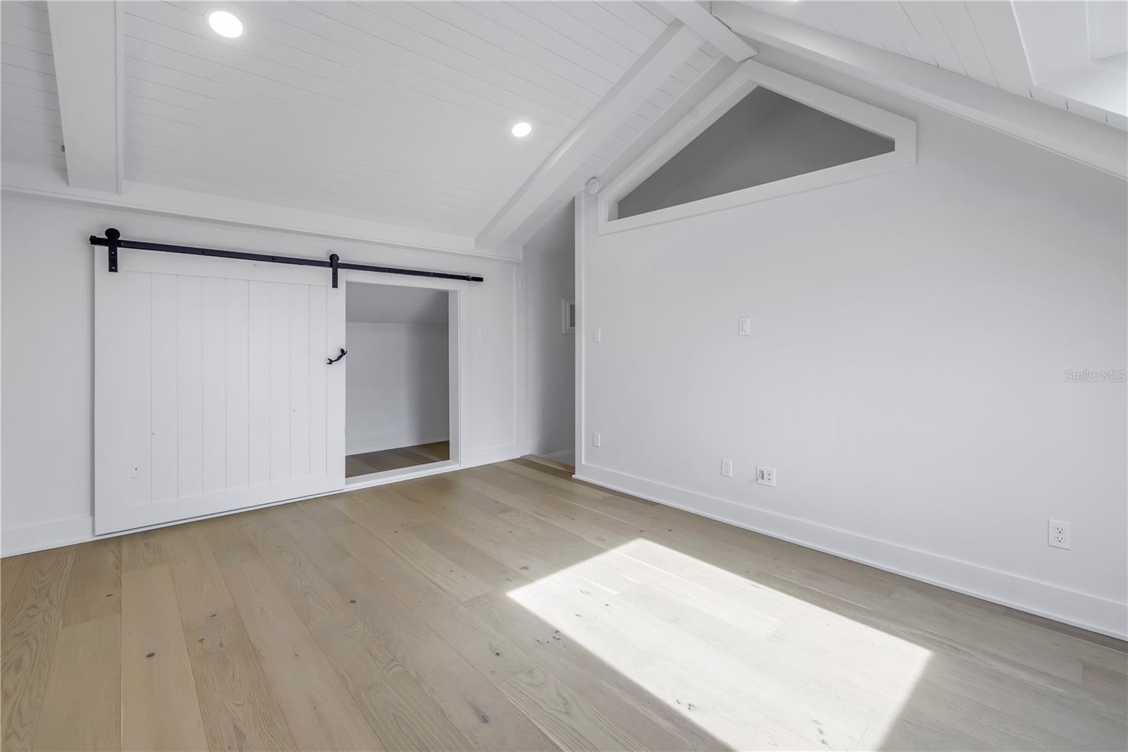 Third bedroom with ceiling shiplap and faux beams, barn doors on the closet