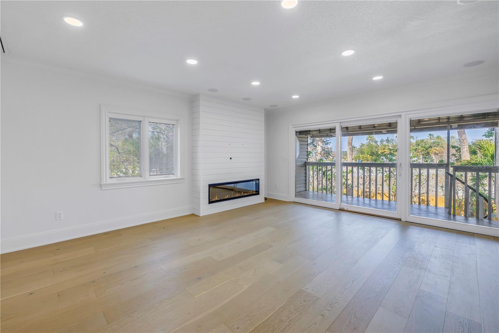 Living room with Electric linear fireplace with shiplap buildout and sliding doors leading to a private balcony