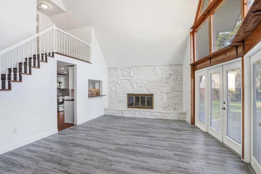 Living Room with pass through to kitchen, staircase to primary suite and wood burning fireplace.