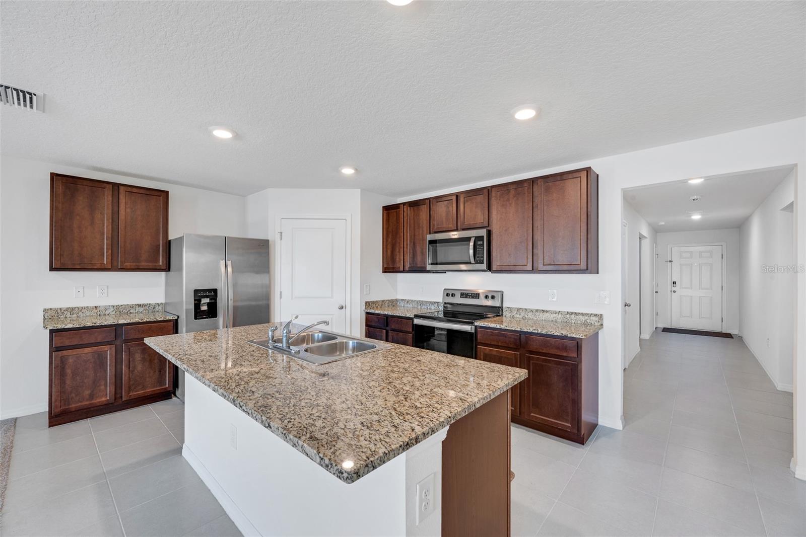 The kitchen has granite counters, stainless steel appliances, kitchen island with sink and large walk-in pantry for added storage.