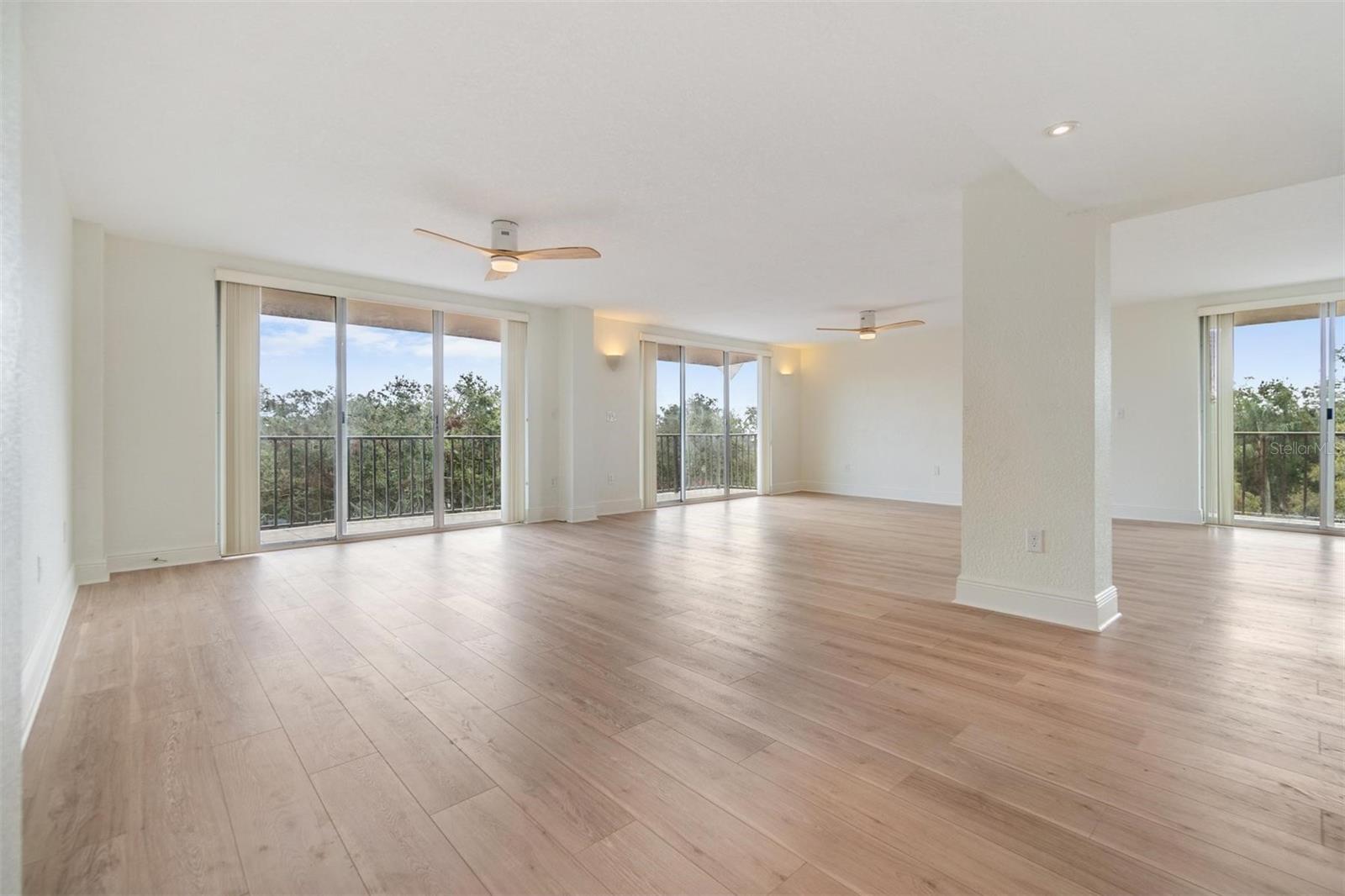 Spacious and open living area with tree top views and neutral paint and gorgeous luxury vinyl flooring.