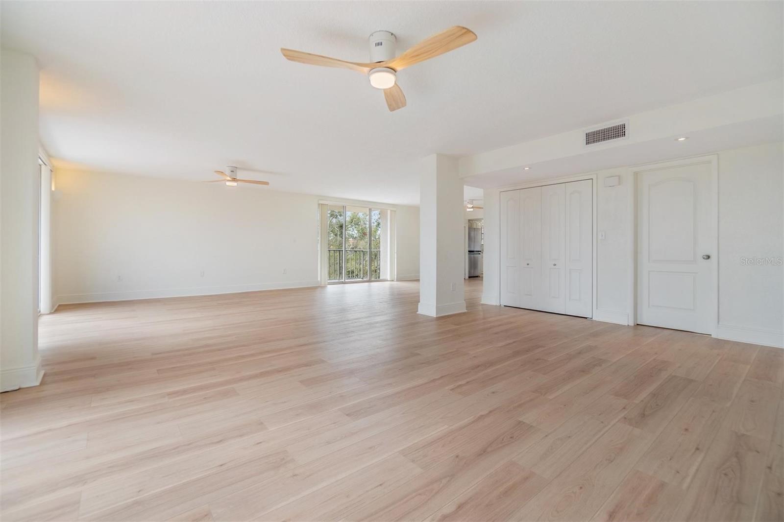 Living room enjoys view from three sets of glass sliders, modern ceiling fans, a large storage closet, and gorgeous luxury vinyl flooring.