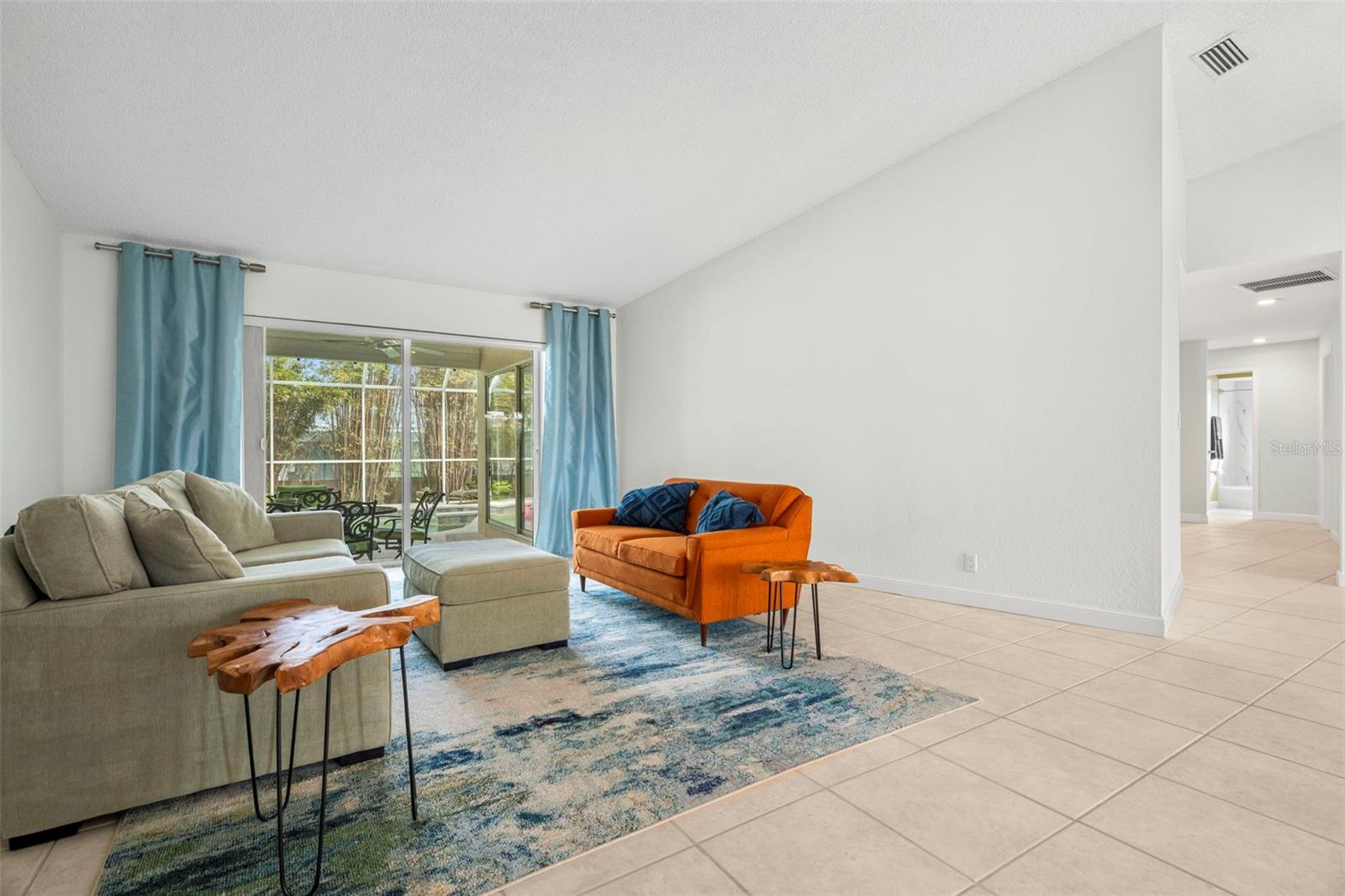 Living room with vaulted ceilings and another access to pool area.