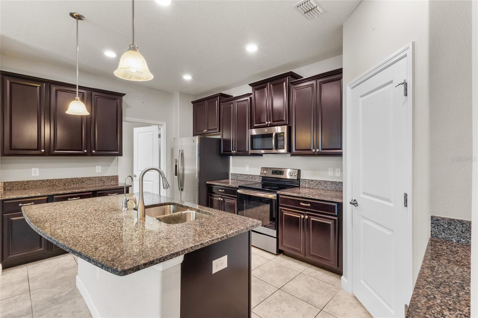 Gorgeous dark cabinetry, granite countertops, and a pantry