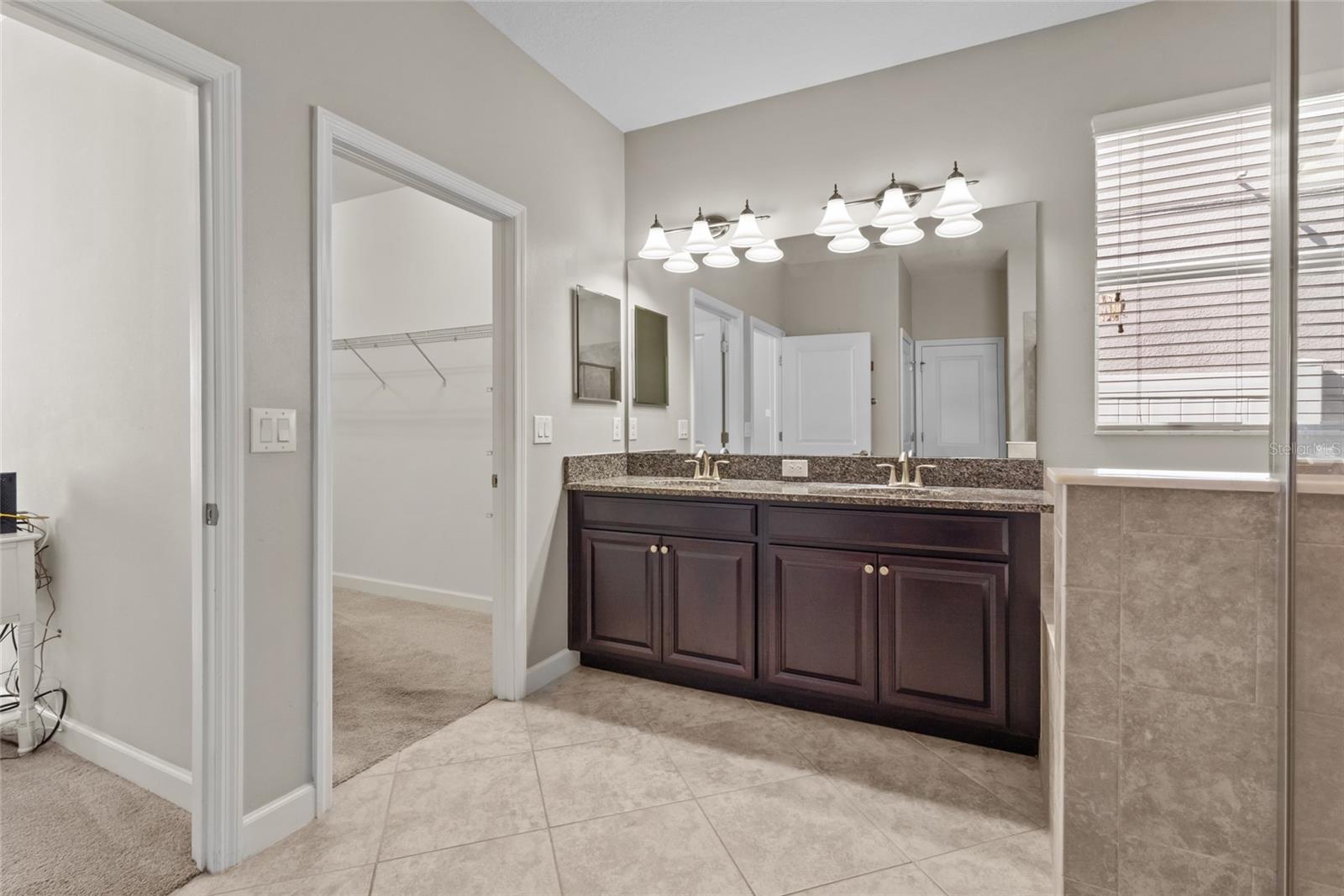 Expansive walk-in closet inside the primary bathroom. Double vanity sinks, soaking tub, and shower