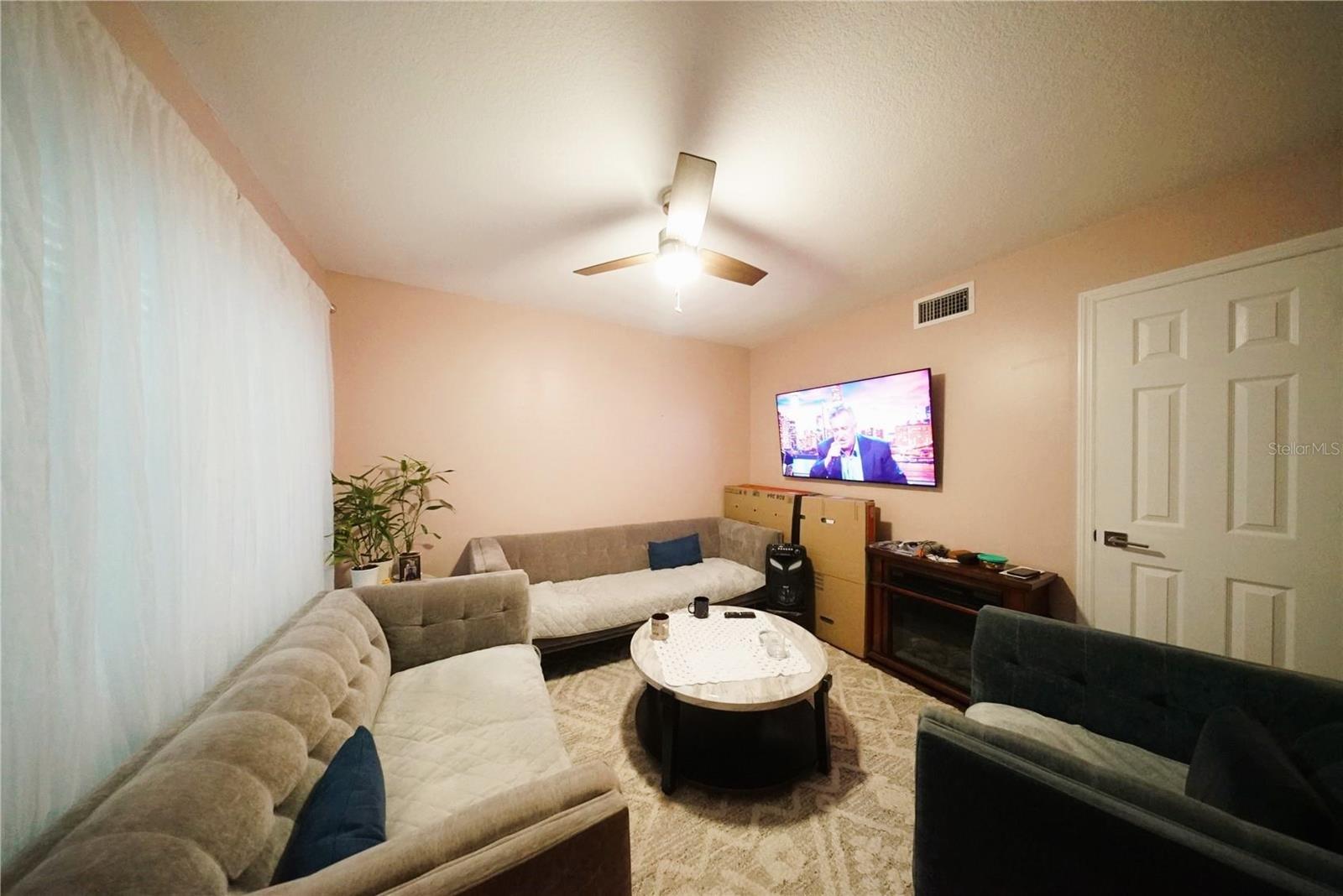 living room with newer ceiling fan, newer windows, newer flooring