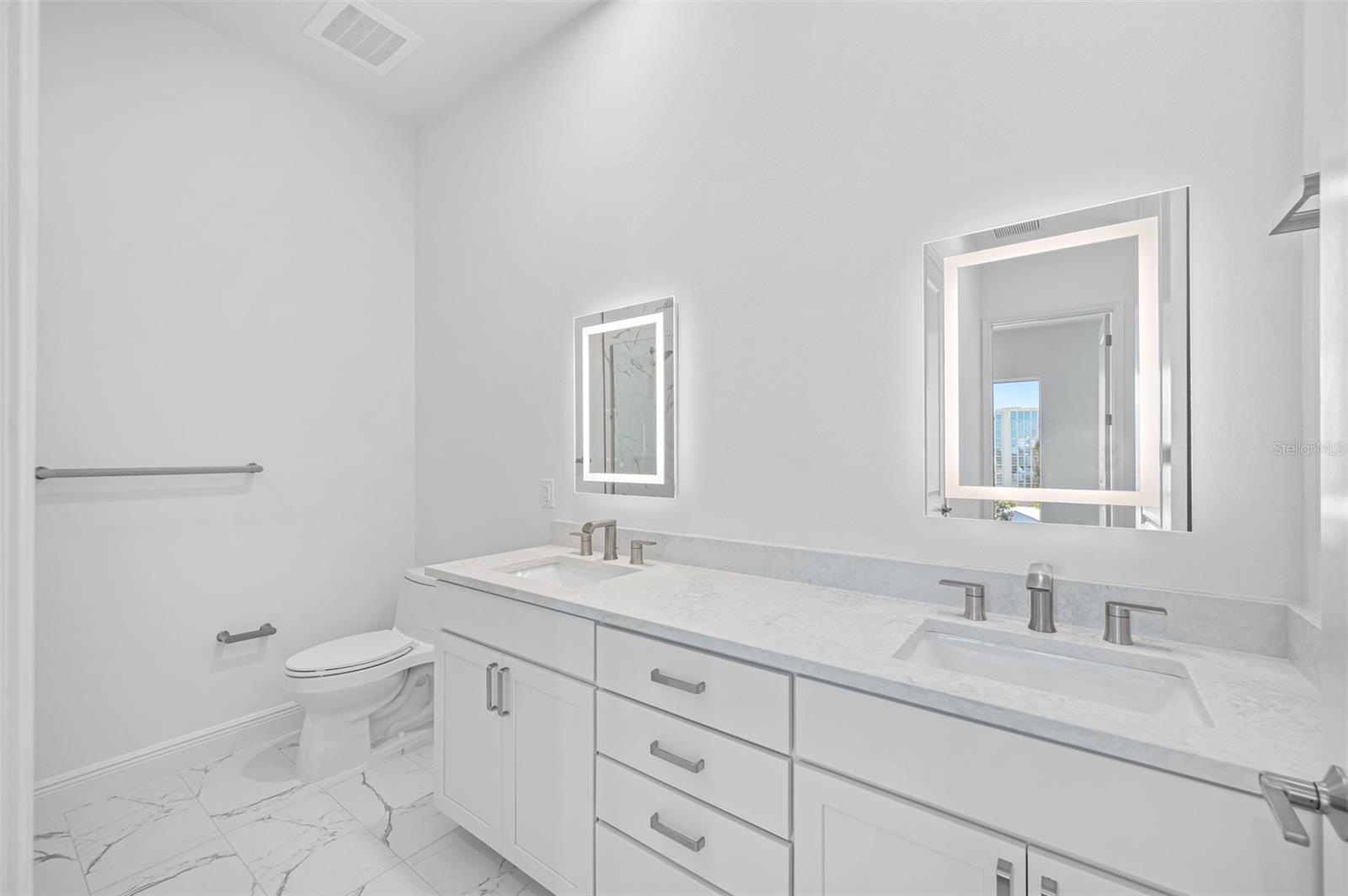 Guest Bath with double vanities, wood cabinetry and lighted vanity mirrors