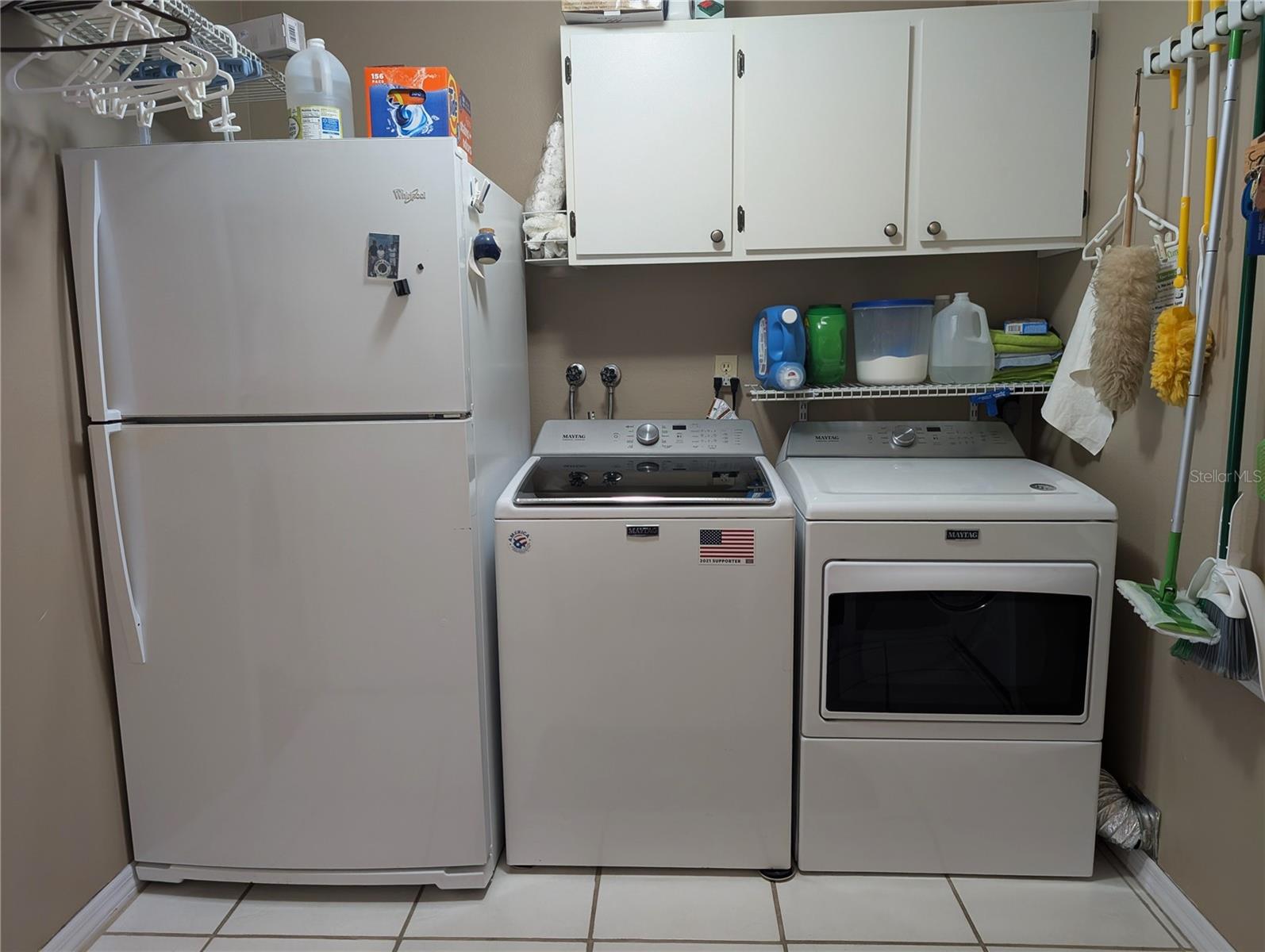 Interior laundry features a 2nd refrigerator for extra storage and a Maytag washer (2019) and dryer set .(2020).  Hallway to living area is on left and garage access is to the right.