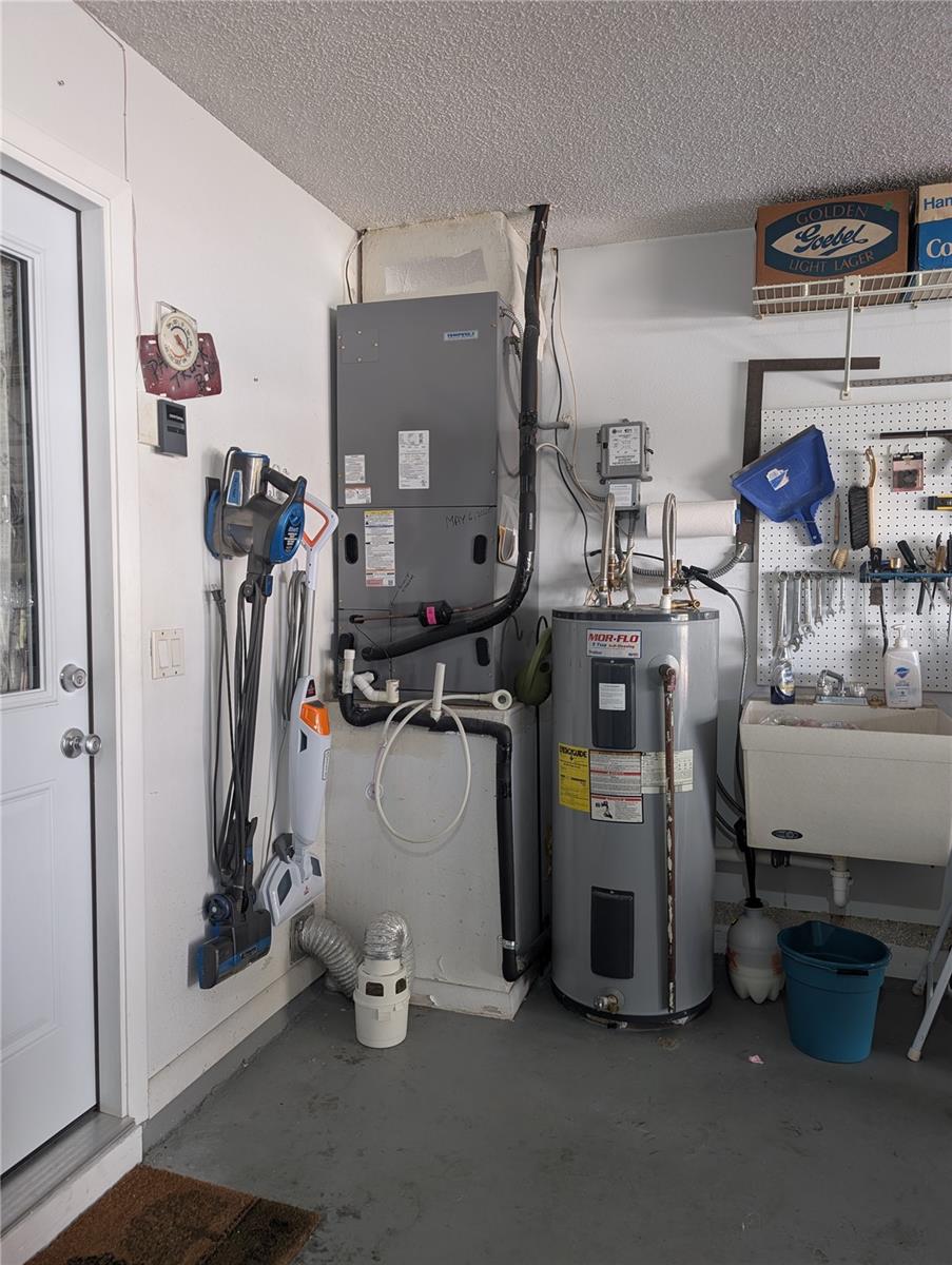 View of Tempstar HVAC system installed in (2020) with digital thermostat located in living room. Garage also houses a utility tub and a 40 gallon Mor Flo electric hot water heater.