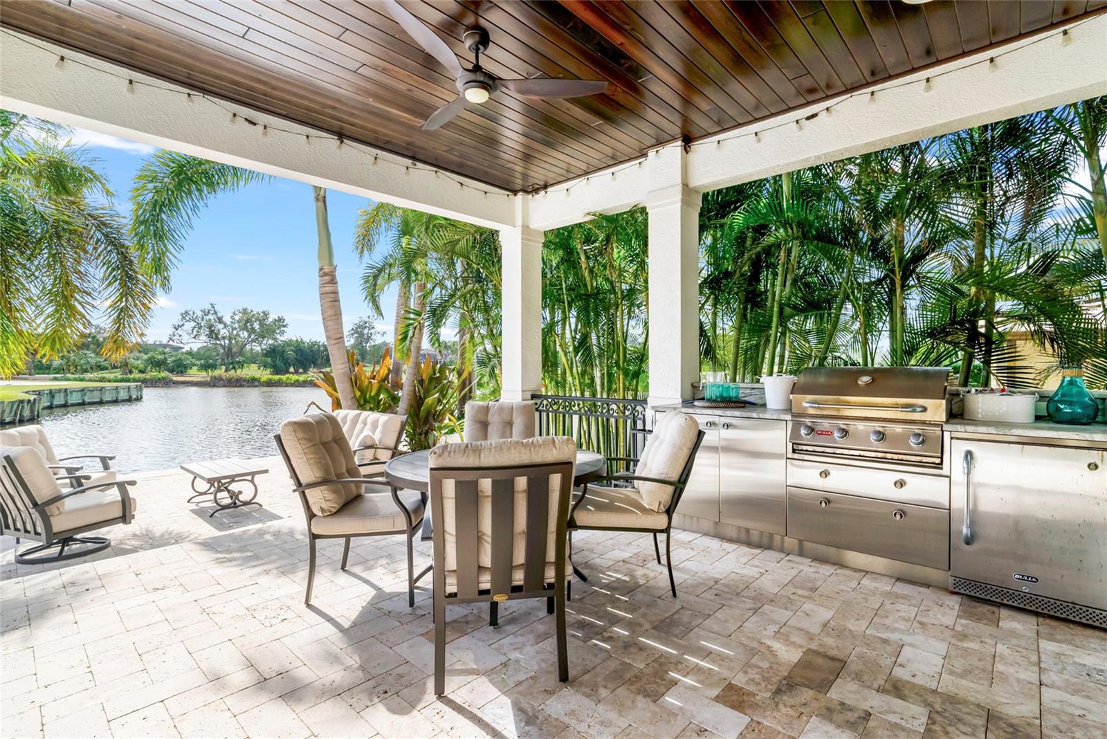 The outdoor kitchen is equipped with a propane grill and refrigerator