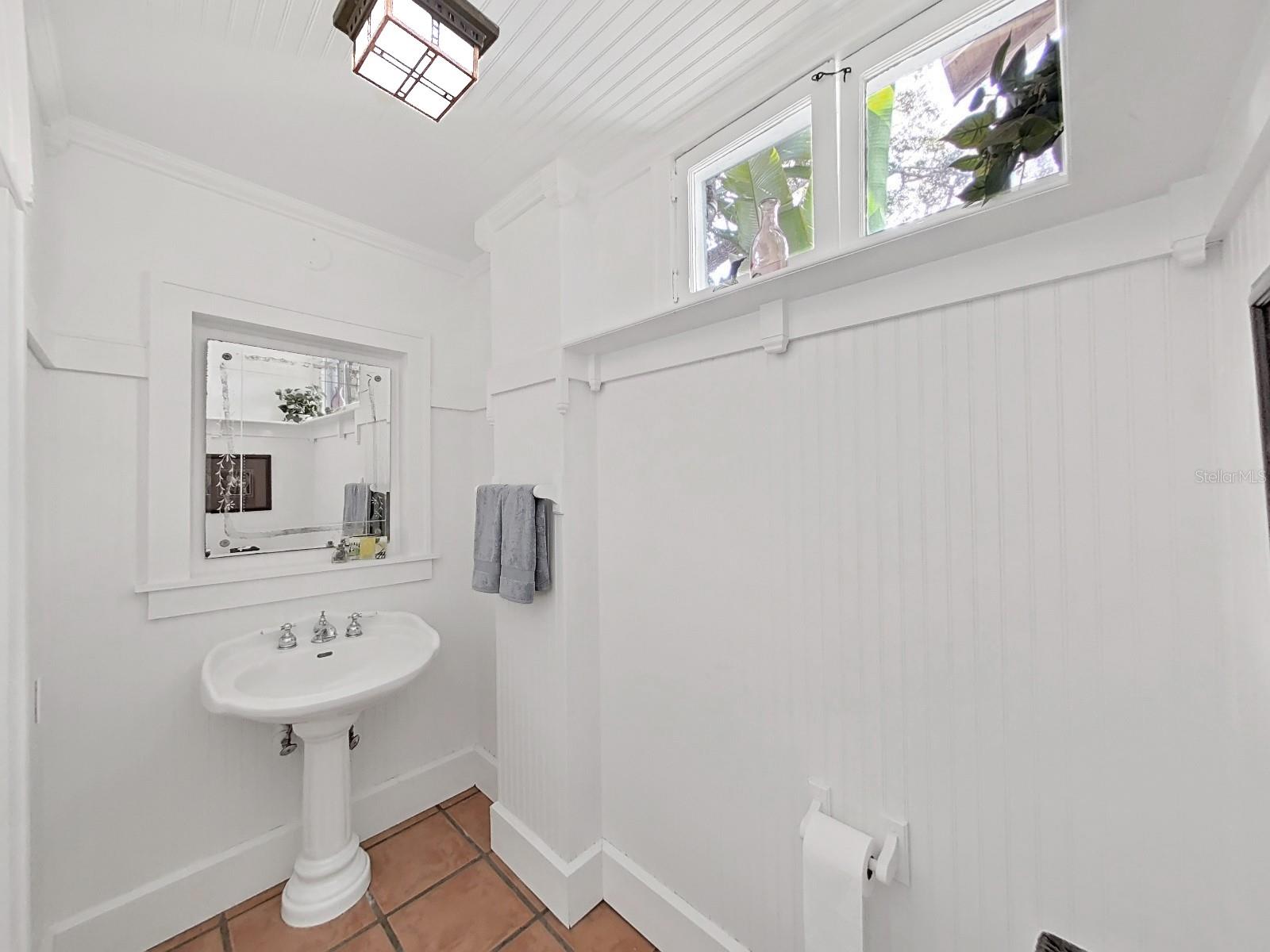 Half bath off breakfast room with pedestal sink and antique mirror