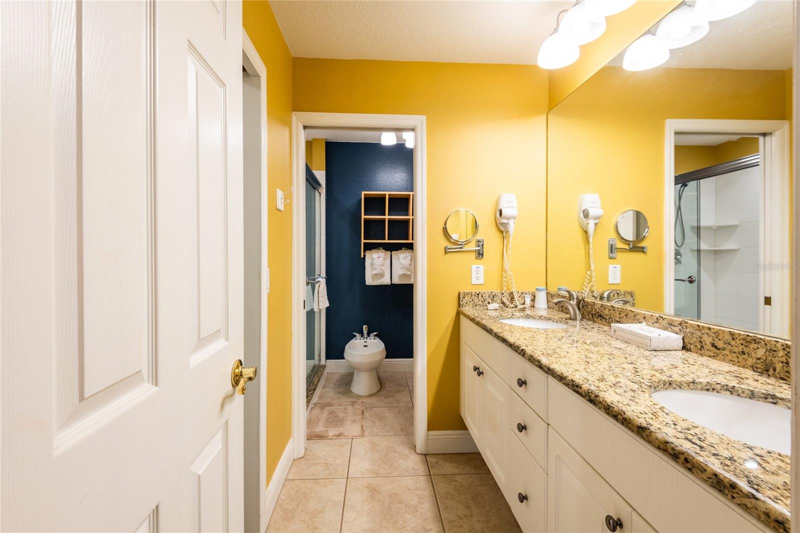 Double high vanity, bidet in background and walk-in closet on left