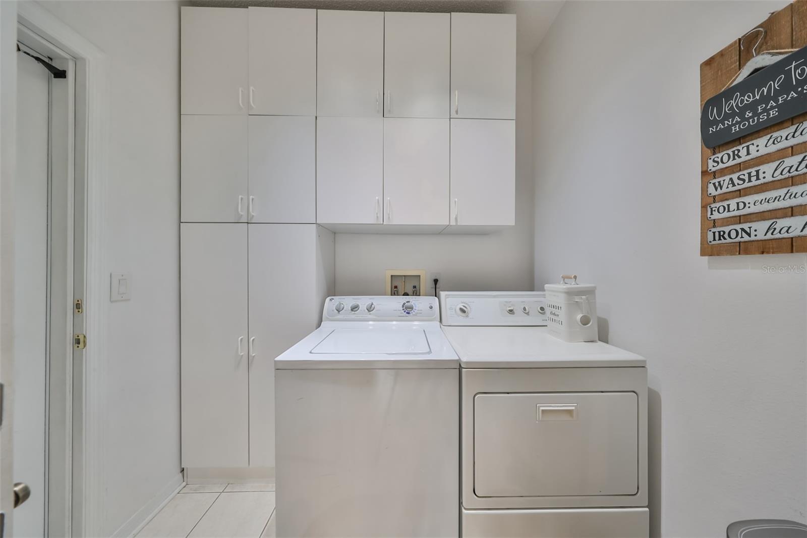 This indoor laundry room has a washer and dryer, as well as tons of storage space for cleaning supplies.