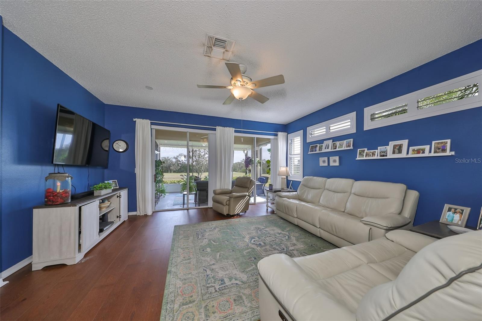 Crisp, white plantation shutters give a coastal feel to the home, along with the stunning floors and coastal paint tones.  A well lit living room in this charming layout with double sliding glass doors for ample natural lighting.