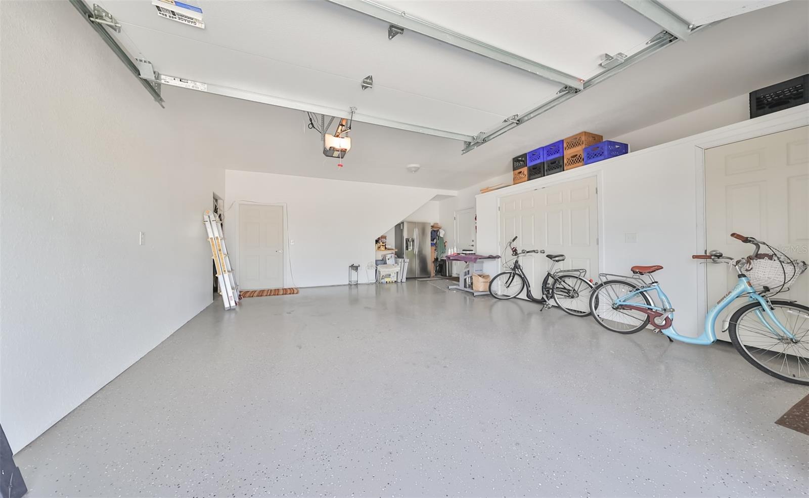 This oversized one car garage has epoxy floors and includes dual double door utility closets for extra storage both downstairs and upstairs, in the far back of the picture, there is a stairwell which leads to the insulated indoor attic loft.