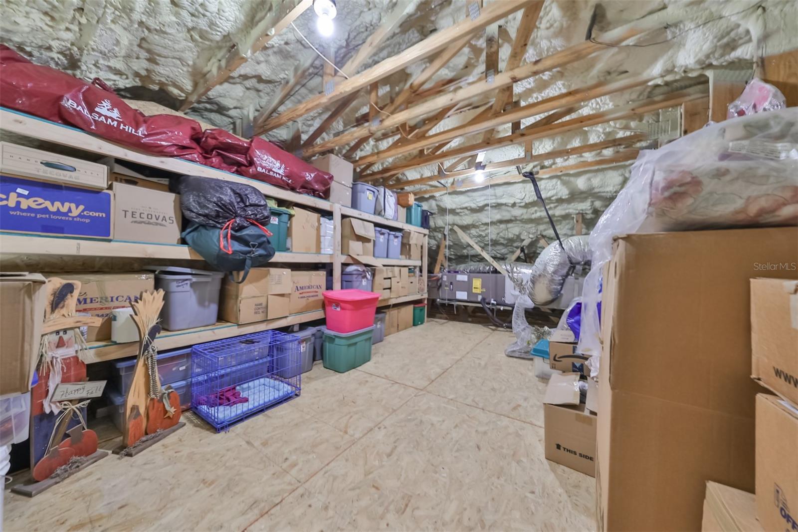 At the top of the stairwell, the attic loft is highly insulated and large enough to comfortably stand and walk around in.  The wood shelving makes storage easy and safe. Notice all of the insulation of this home.