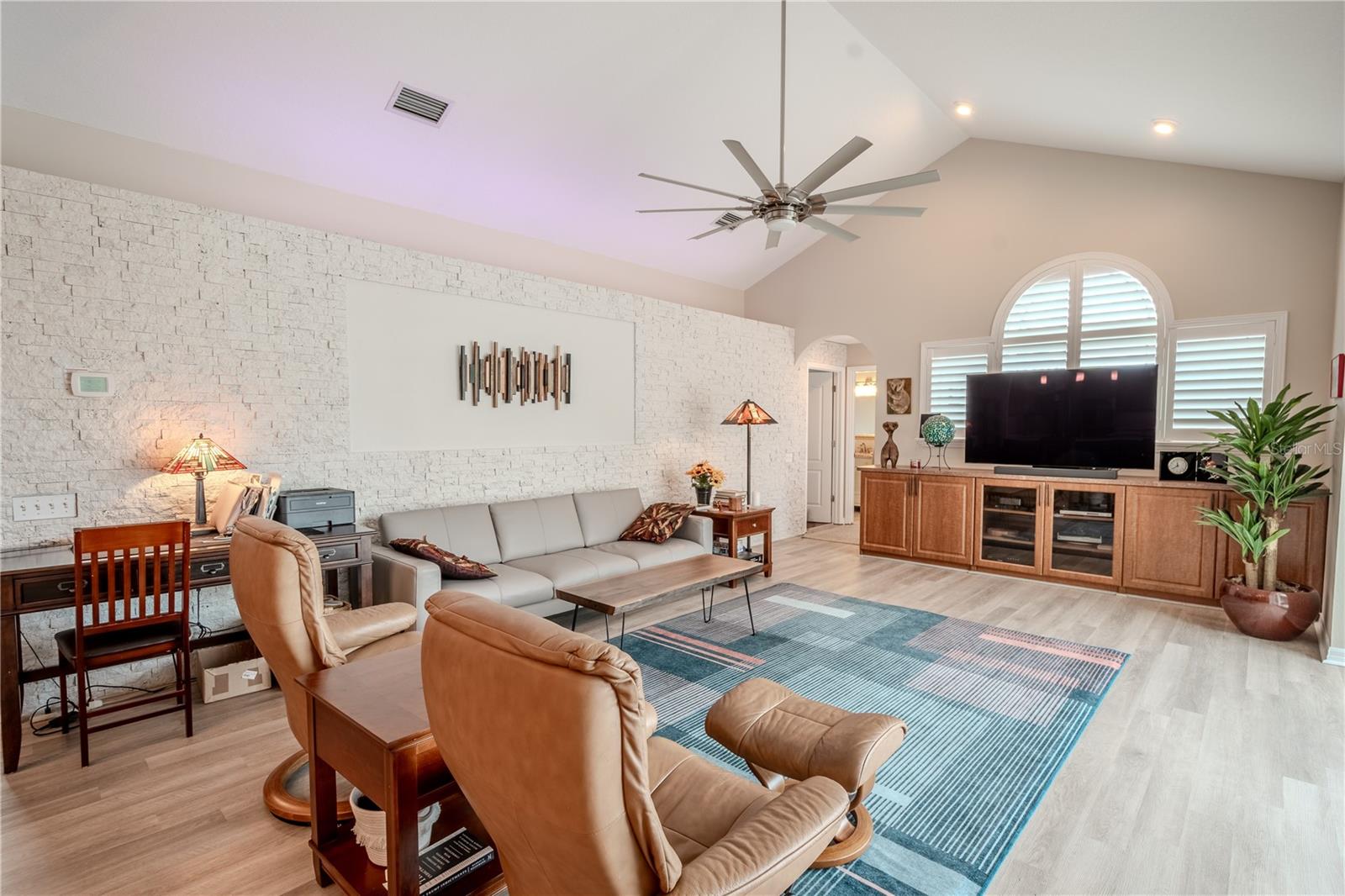 The family room features an architecturally detailed accent wall and an arched window with shutters.