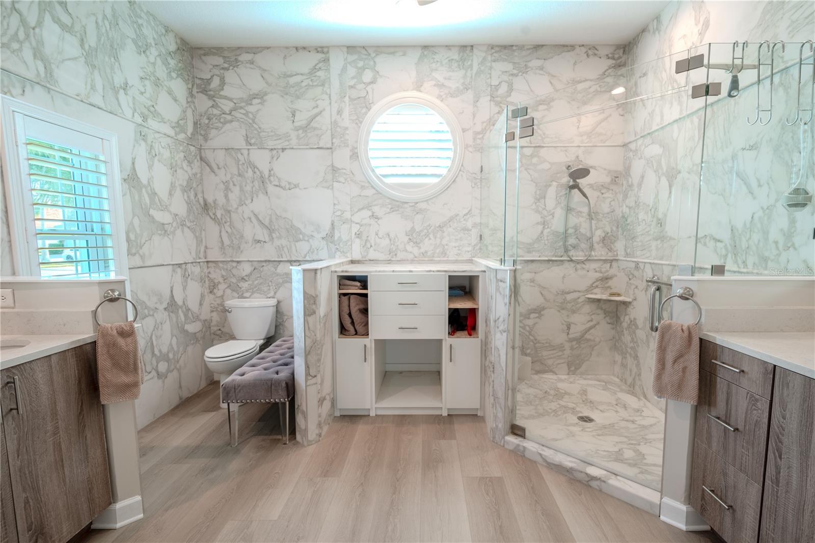 The primary ensuite completely redesigned and upgraded features a large, glass enclosed walk-in shower, built in cabinetry, and a pair of his and her mirrored vanities.