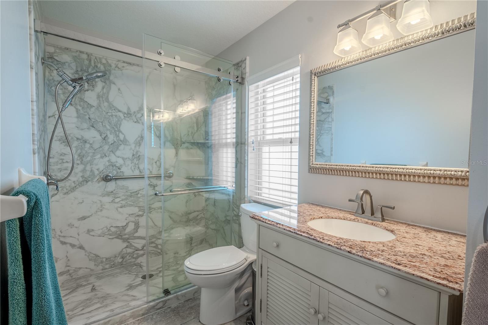 Bathroom 2 features a mirrored vanity with down light fixture and a glass enclosed walk-in shower.