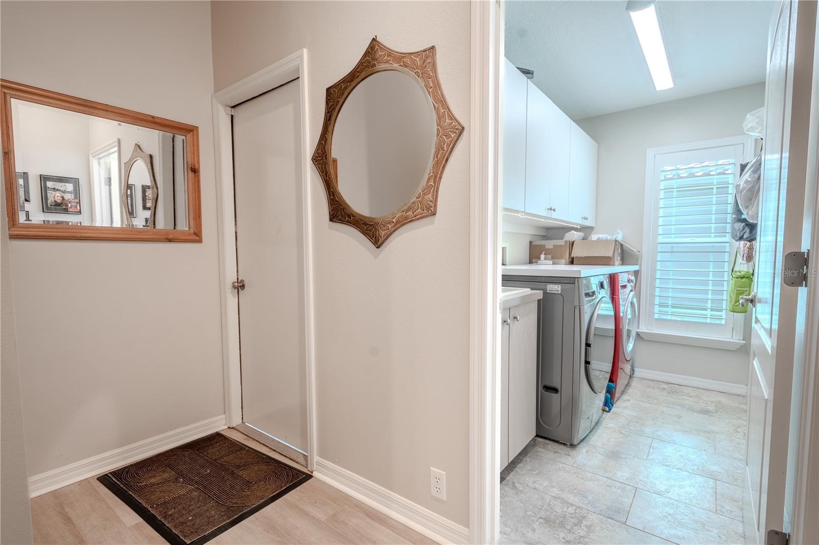 The laundry room has front load washer and dryer, a wall of built-in cabinets above and a utility sink with additional storage.