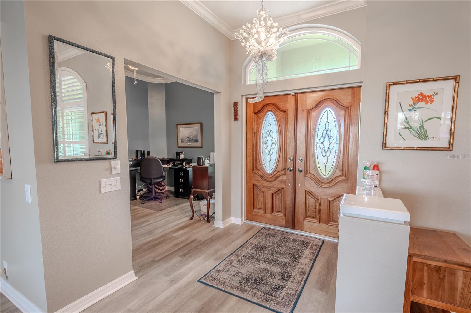 The double front doors with decorative glass, a transom window and chandelier illuminate the foyer.