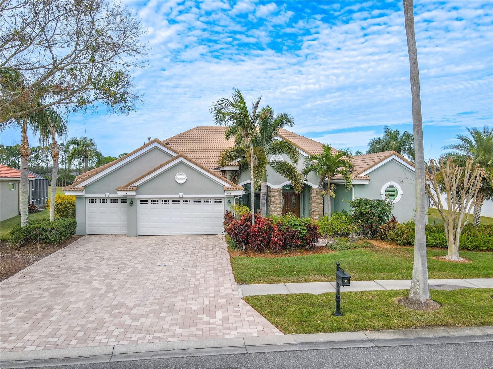 Mature tropical landscaping and pavered drive and entryway give elevated curb appeal.