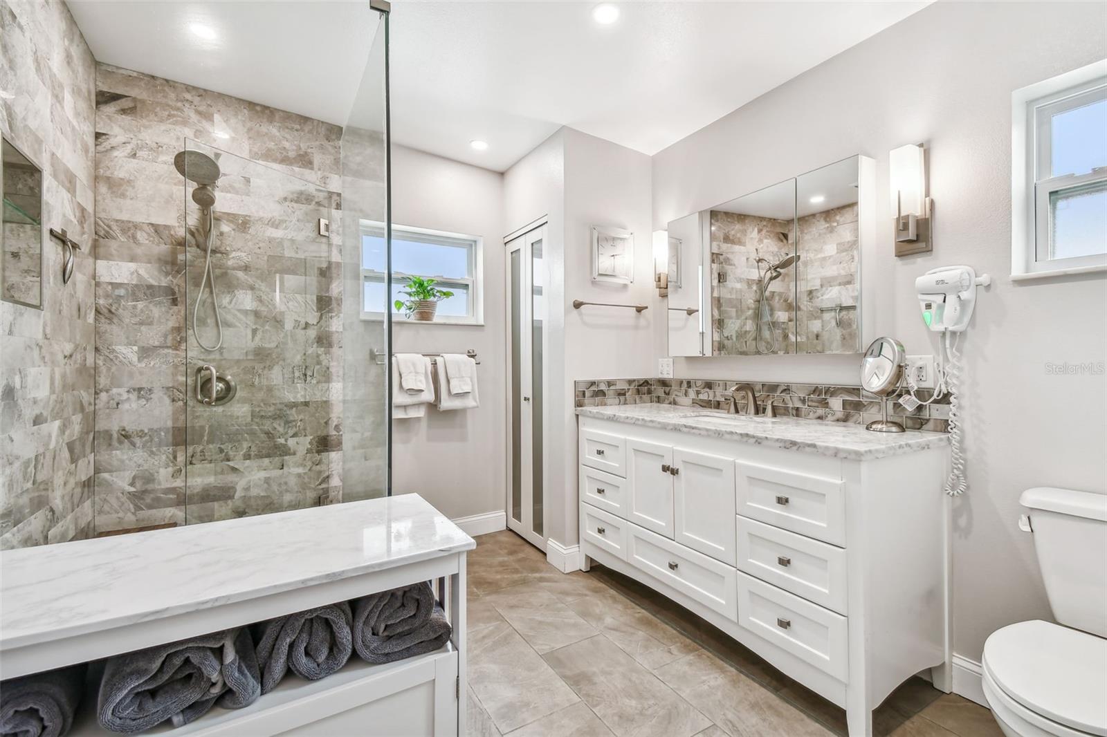 Primary ensuite bathroom, large marble walk in shower, linen closet and extended vanity