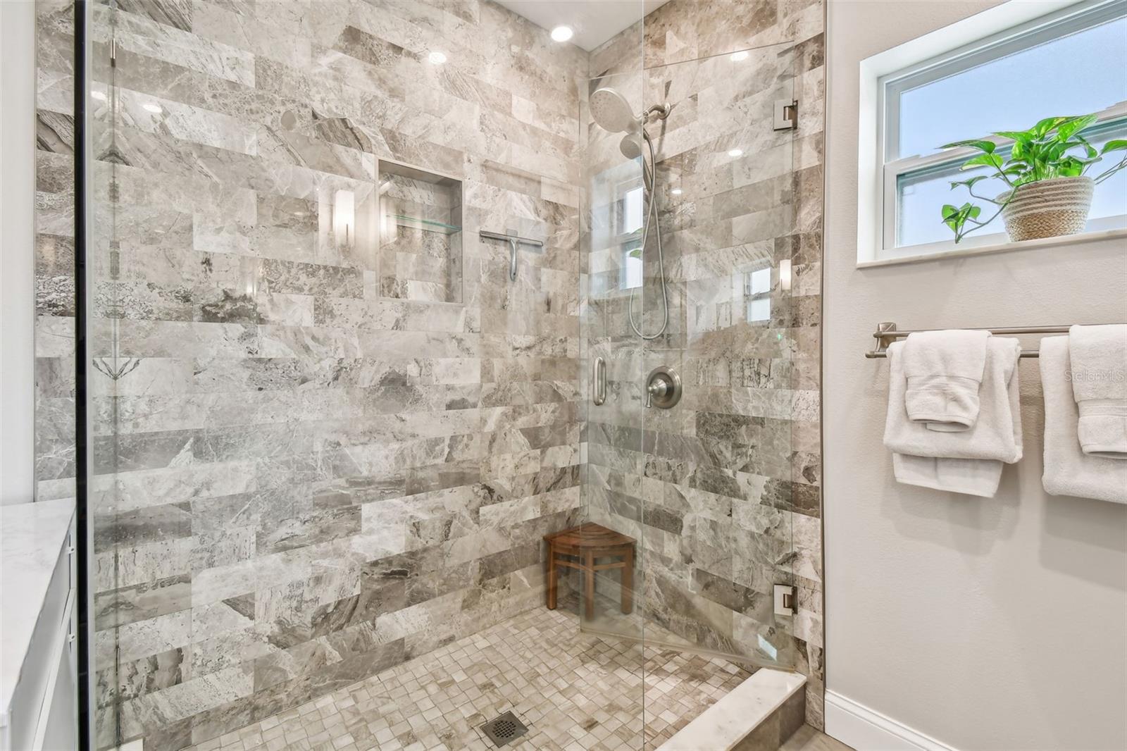 Marble walk in shower with glass panels and door entry