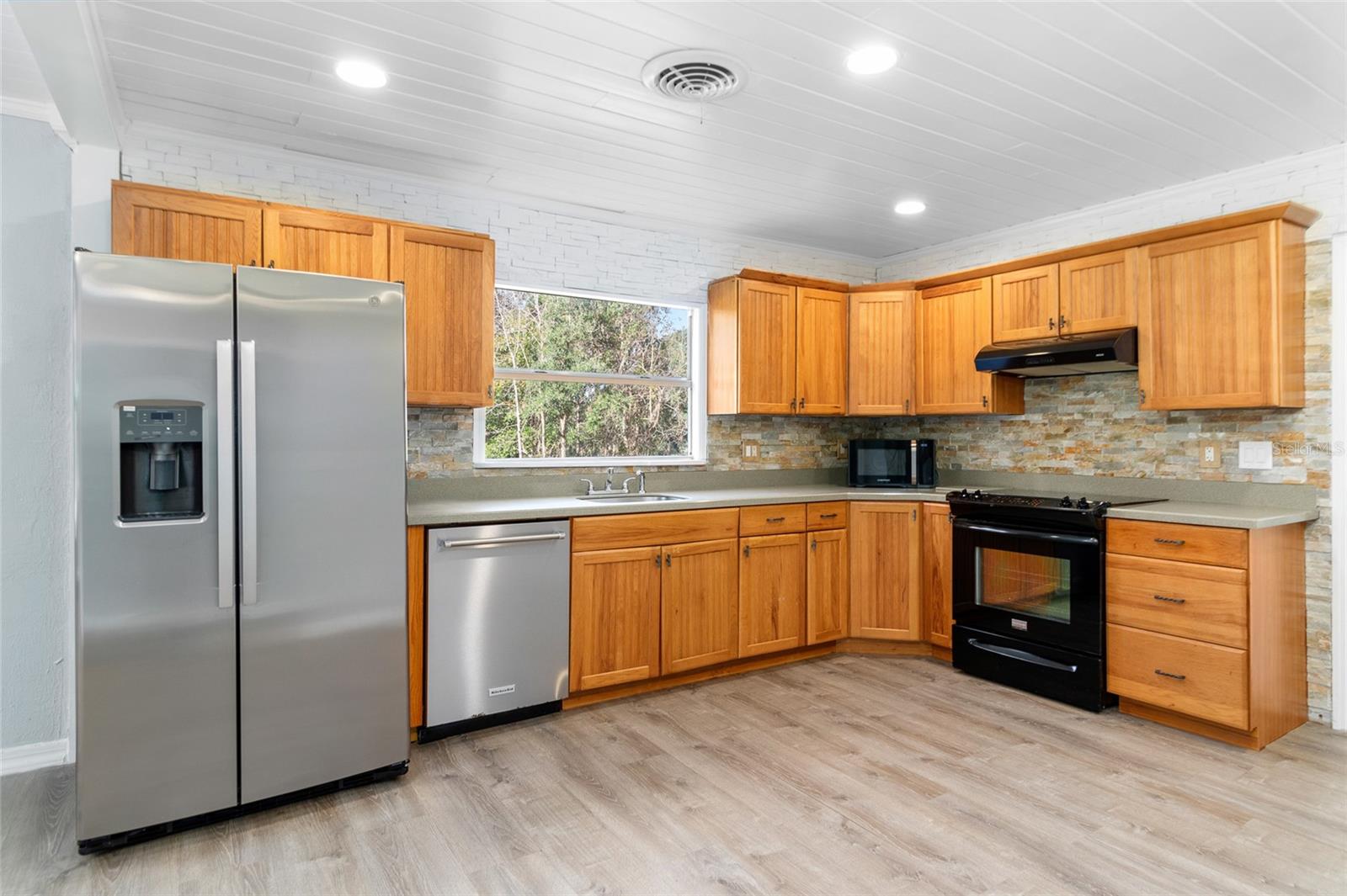 This kitchen is lovely. It has custom wood cabinetry and appliances.  It also has a new stainless steel refrigeratorl and solid surface countertops.