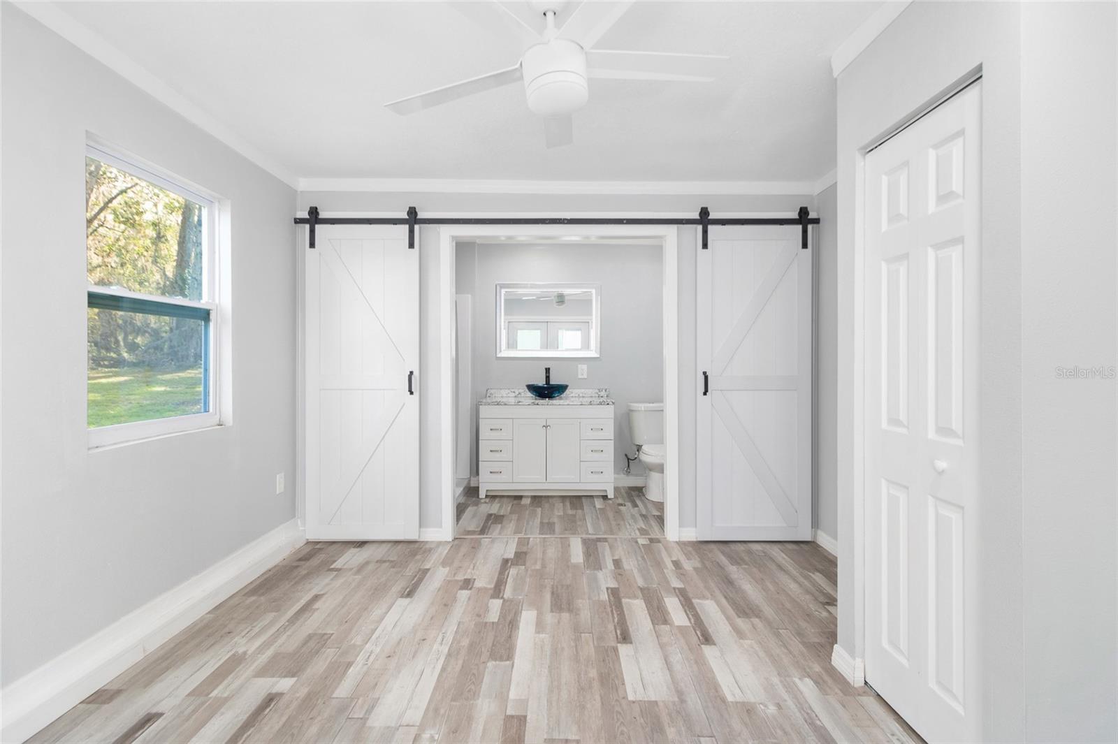 Primary bedroom with French doors and barndoors to enter the bathroom