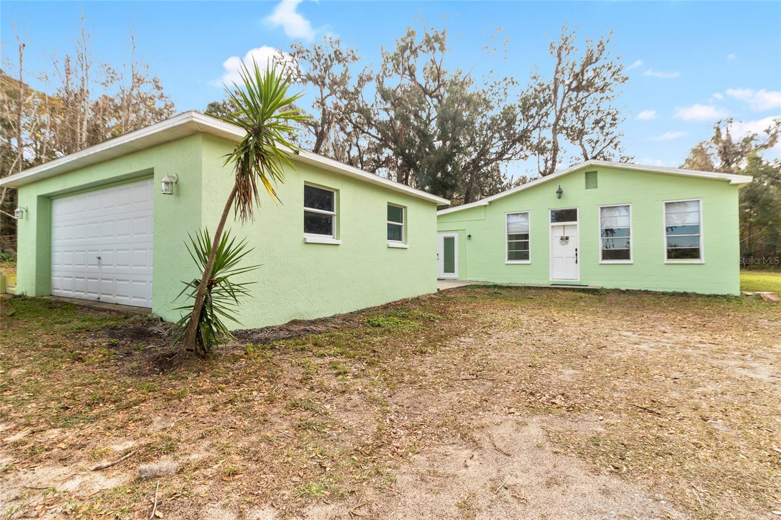 This lovely view showcases a serene 2.5 acre property with a 3/2 cement block one story home in an X flood Zone. The property includes a detached 2-car garage, a storage shed, and an RV dumpstation. The property is lined with trees for privacy. The property is surrounded by nature, and one neighbor has a vast horse and cow pasture with acres of land.