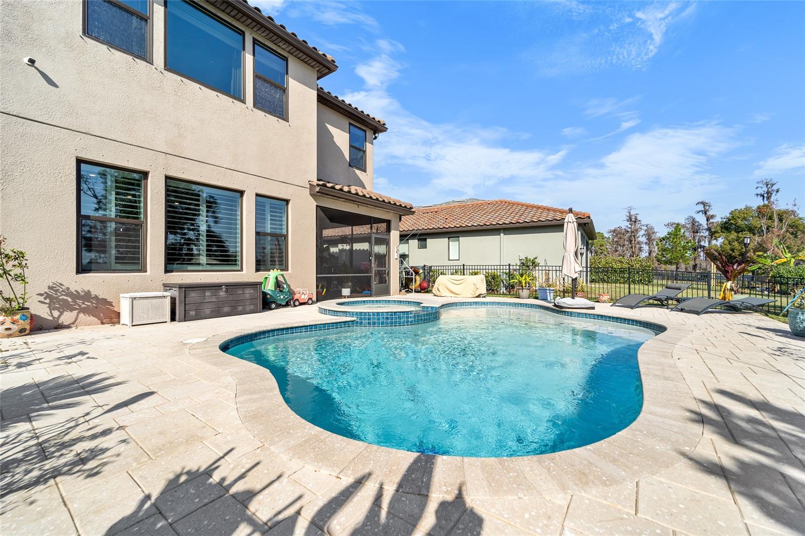 Back of house with pool and screened lanai, fully fenced yard