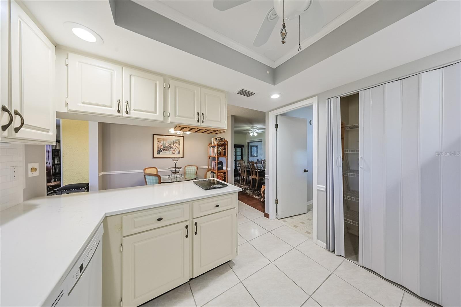 Kitchen is updated with tile flooring and includes lots of solid wood cabinetry, as well as large pantry seen to the right in this photo.