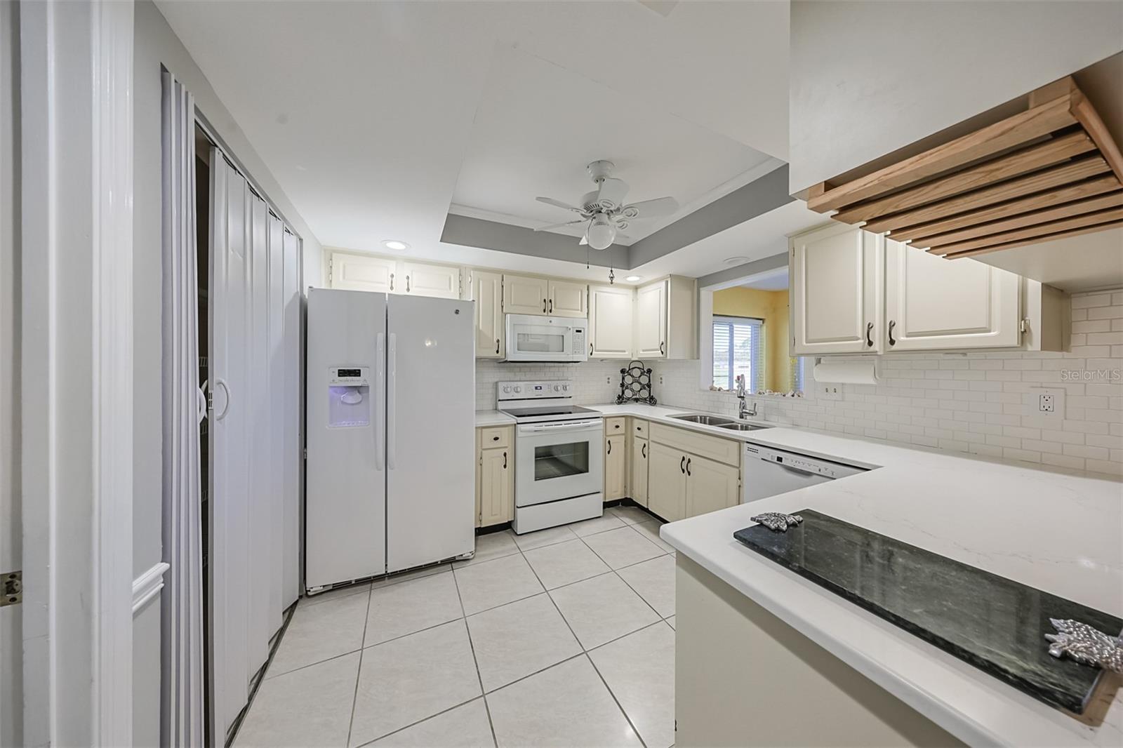 Kitchen includes newer appliances, lots of lovely Corian countertop space, a pantry along a full wall and a large pass-through window so that you can see/talk to anyone in the Florida room or enjoy the vast green space and Florida sunshine outside.